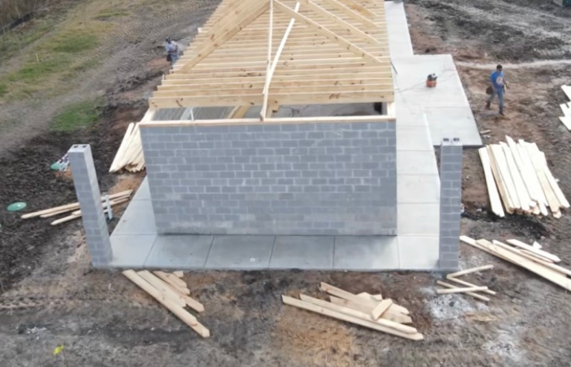 Construction of a building: Cinder block walls, wooden roof frame, concrete patio.