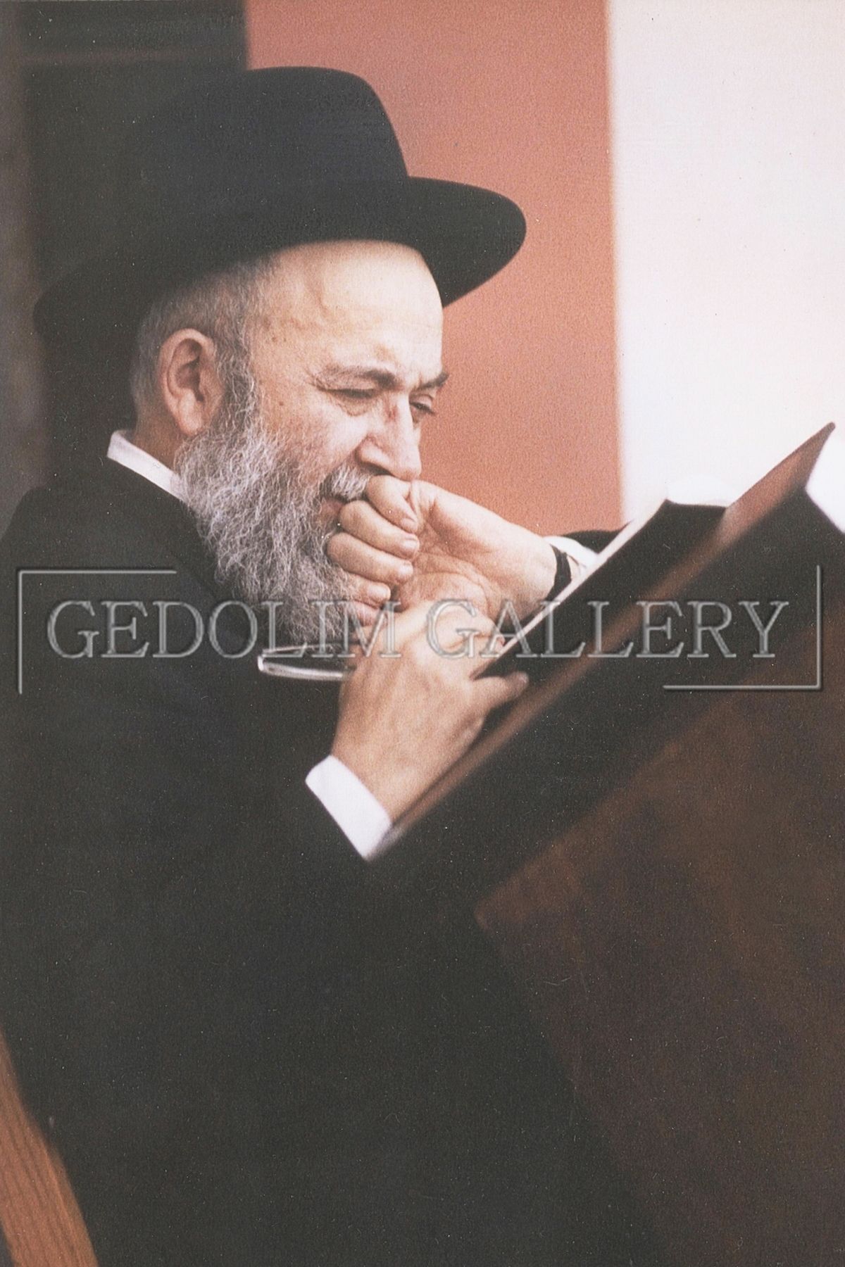 A man with a beard wearing a hat is reading a book