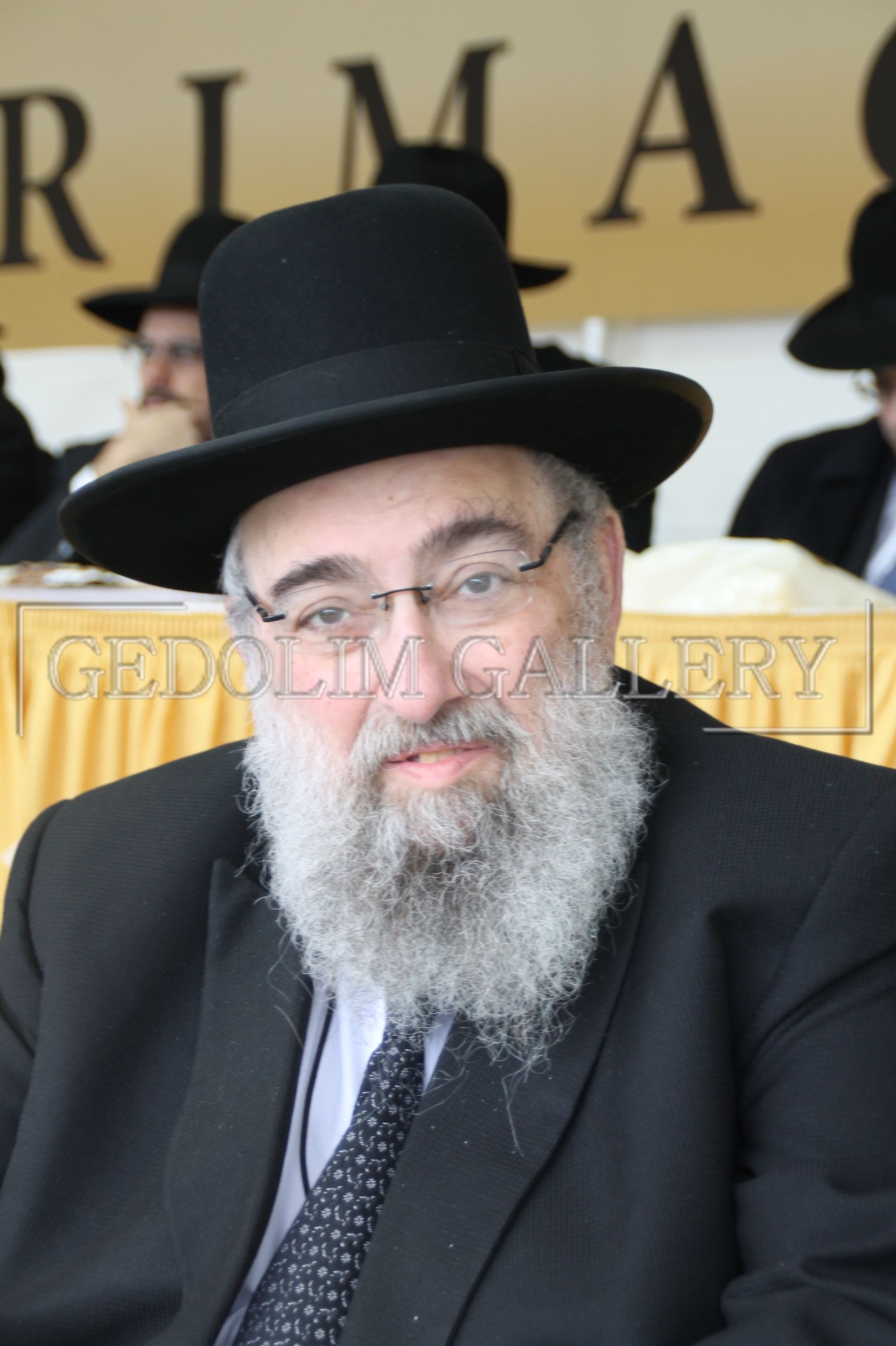 A man with a beard wears a black hat and glasses