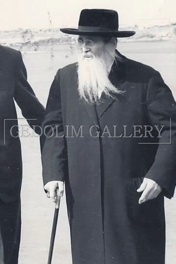 A man with a beard is walking with a cane in a black and white photo