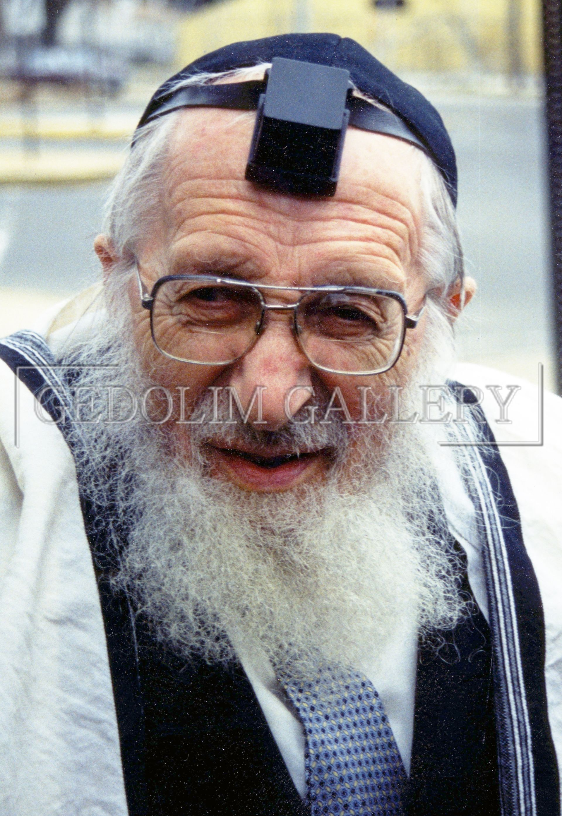 A man with a beard wearing glasses and a torah on his head