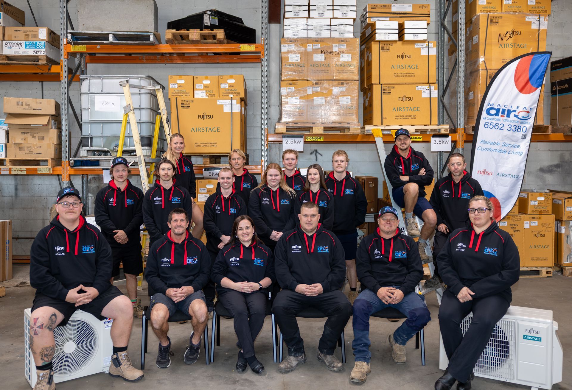 A Group Of People Standing In Front Of Two Macleay Trucks — Macleay Air In West Kempsey, NSW