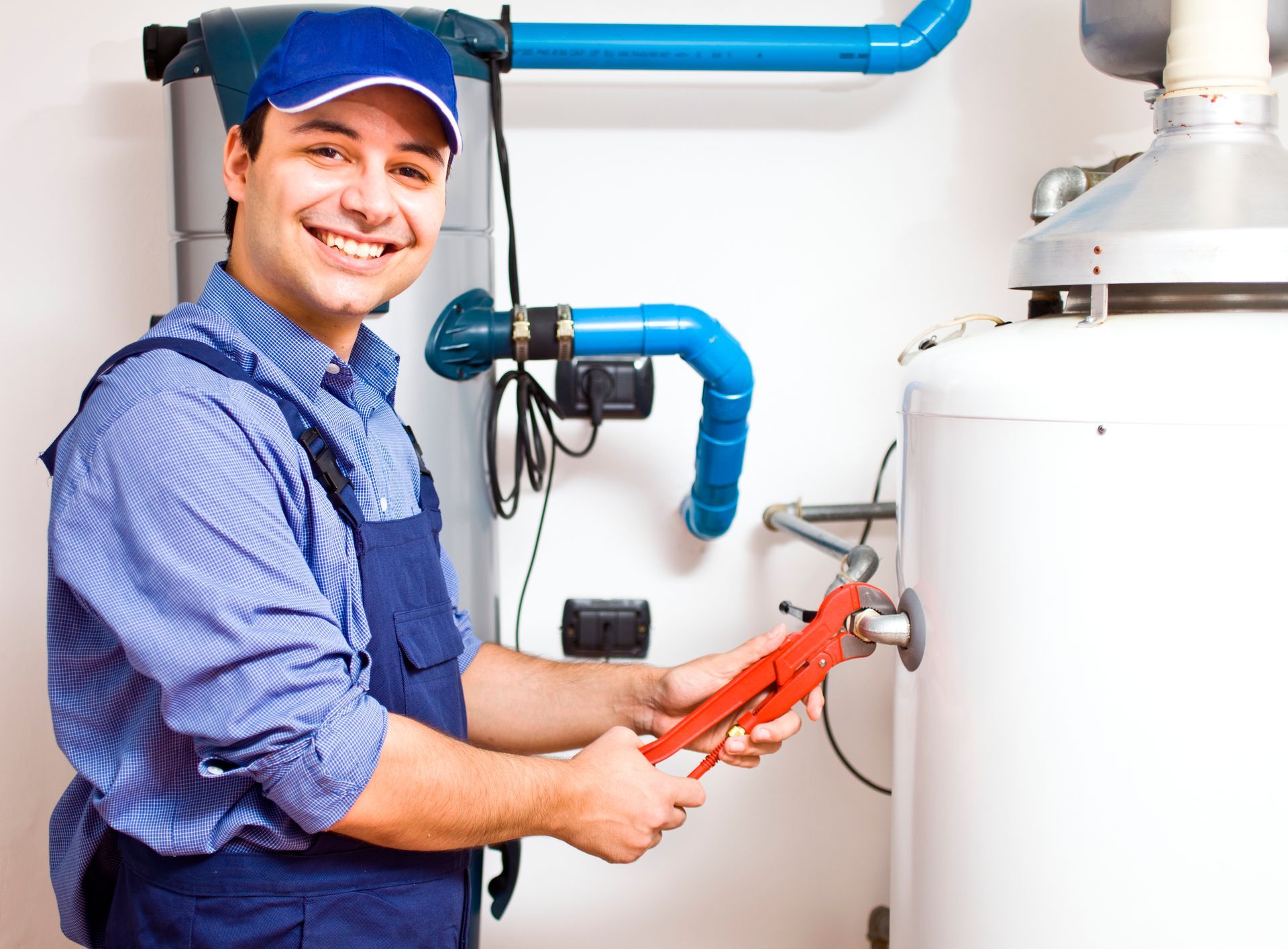 A plumber is fixing a water heater with a wrench.