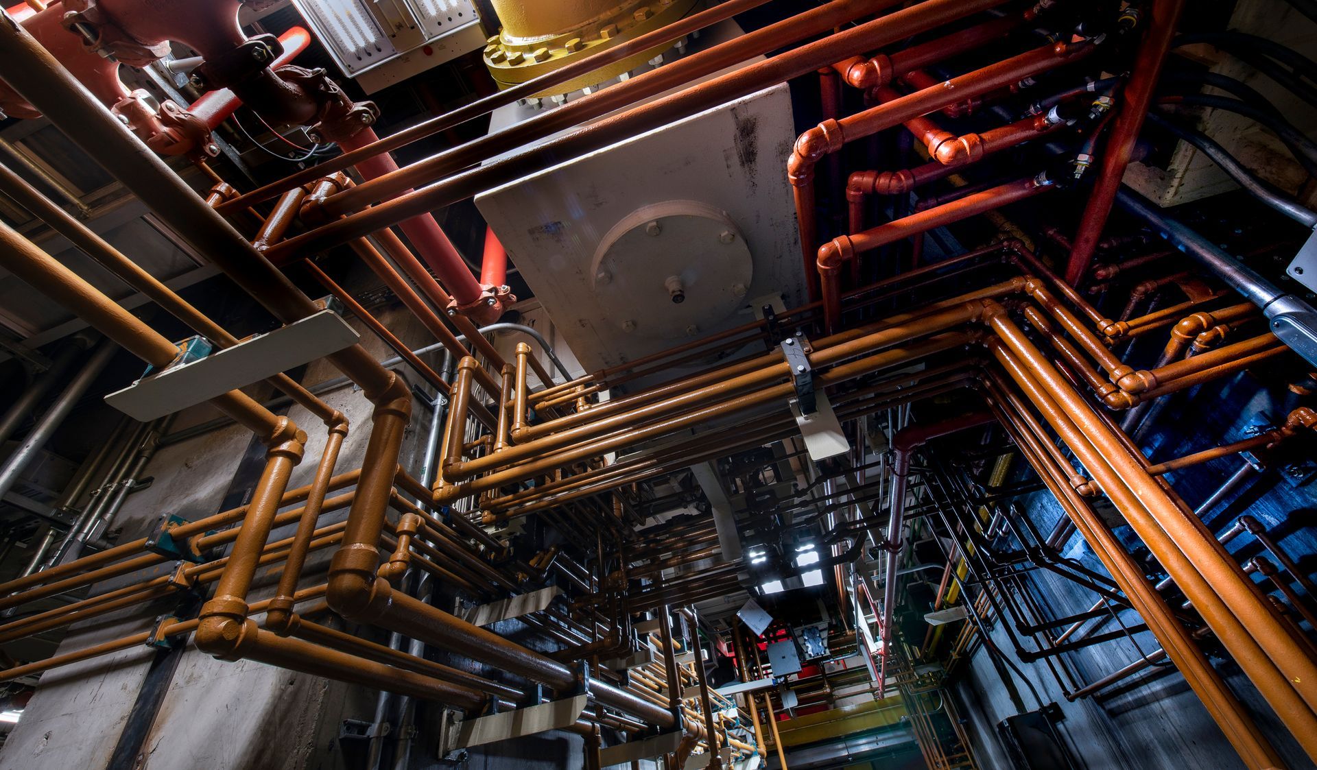 A bunch of pipes are hanging from the ceiling of a building