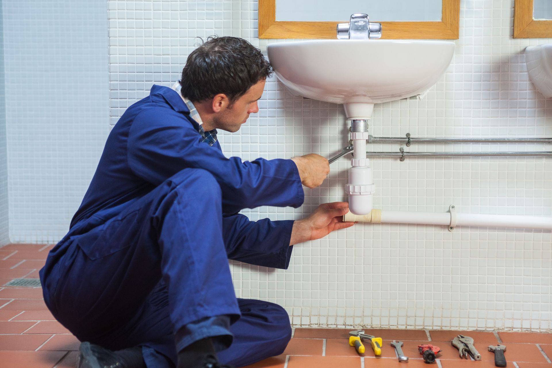 A plumber is fixing a sink in a bathroom.