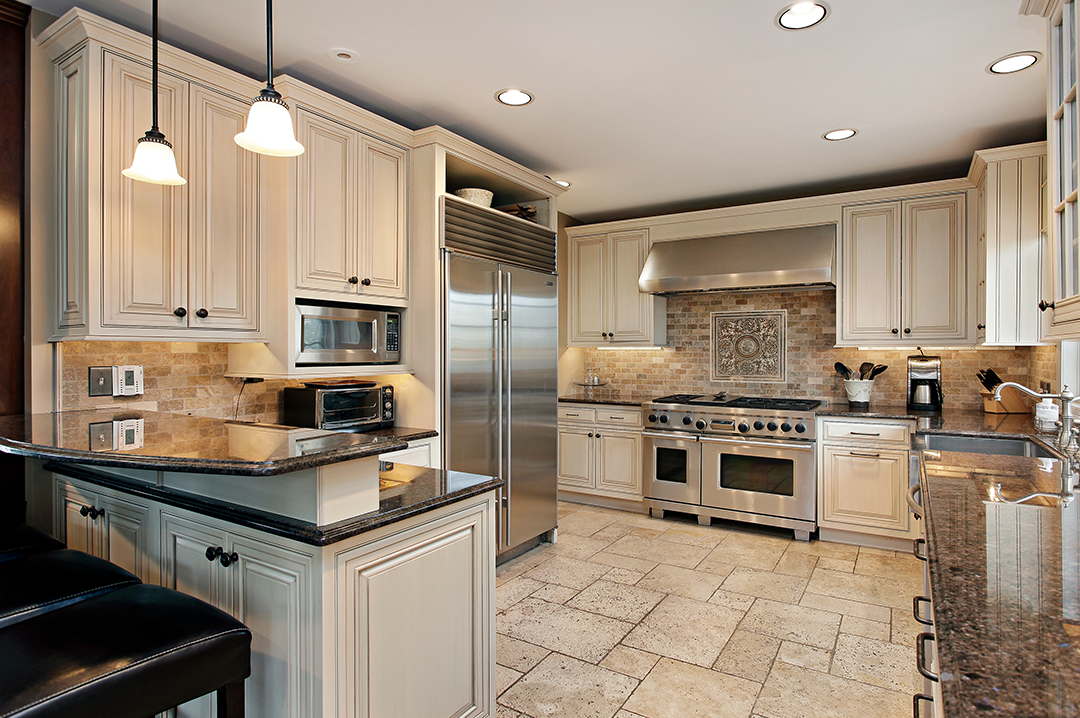 Modern kitchen with floor to ceiling cabinets, neutral tones, tile floor and recessed lighting.