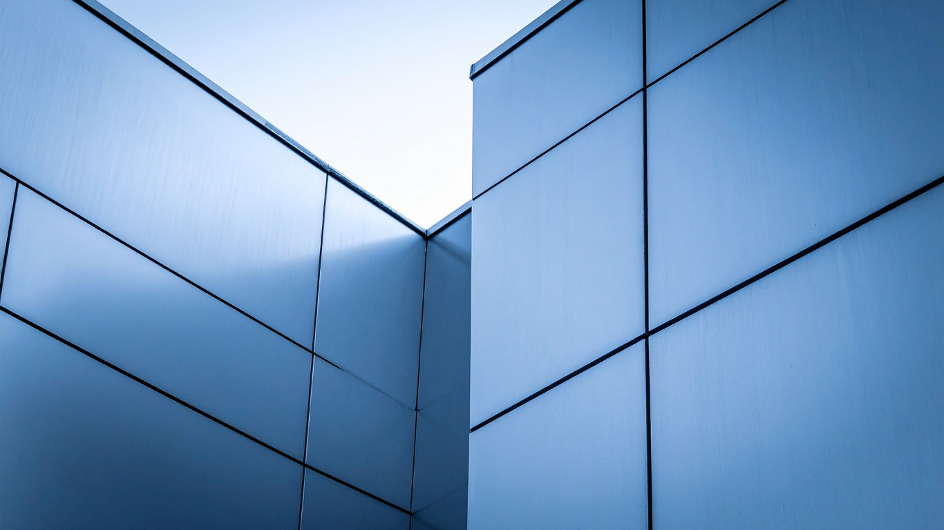 Blue, geometric building facade with grid pattern and angled corner.