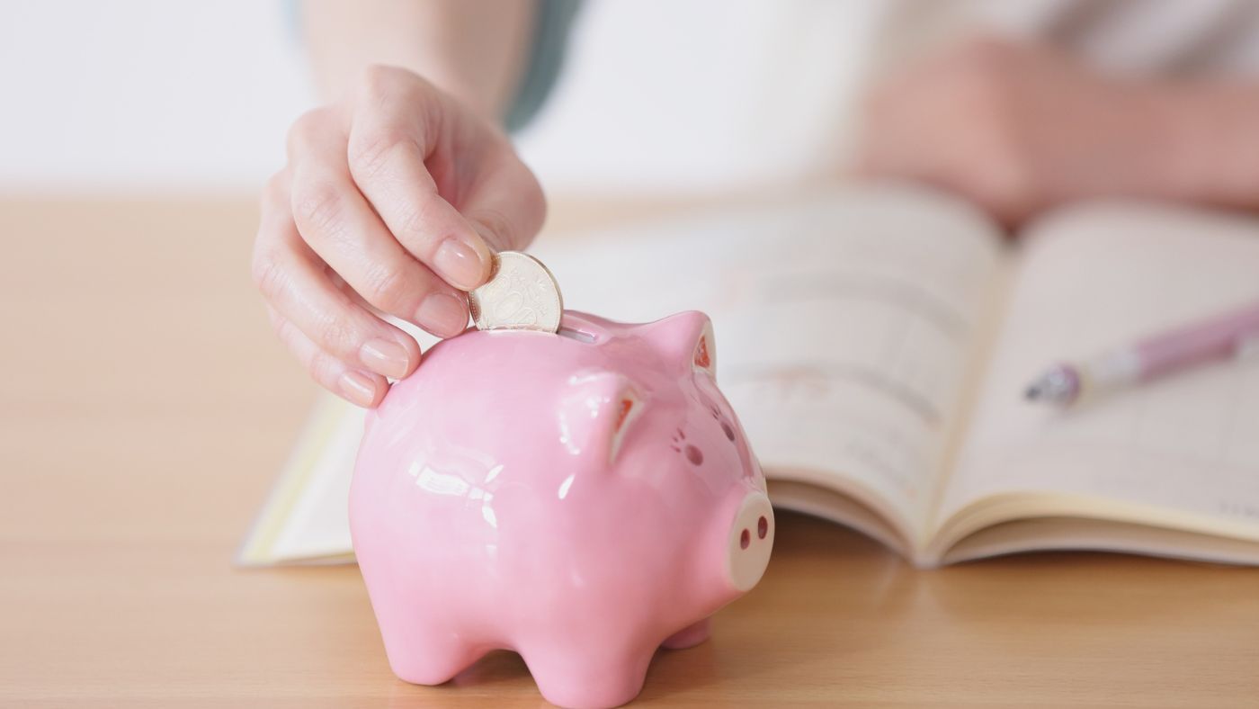 Hand putting a coin into a piggy bank as a symbol of energy and cost savings