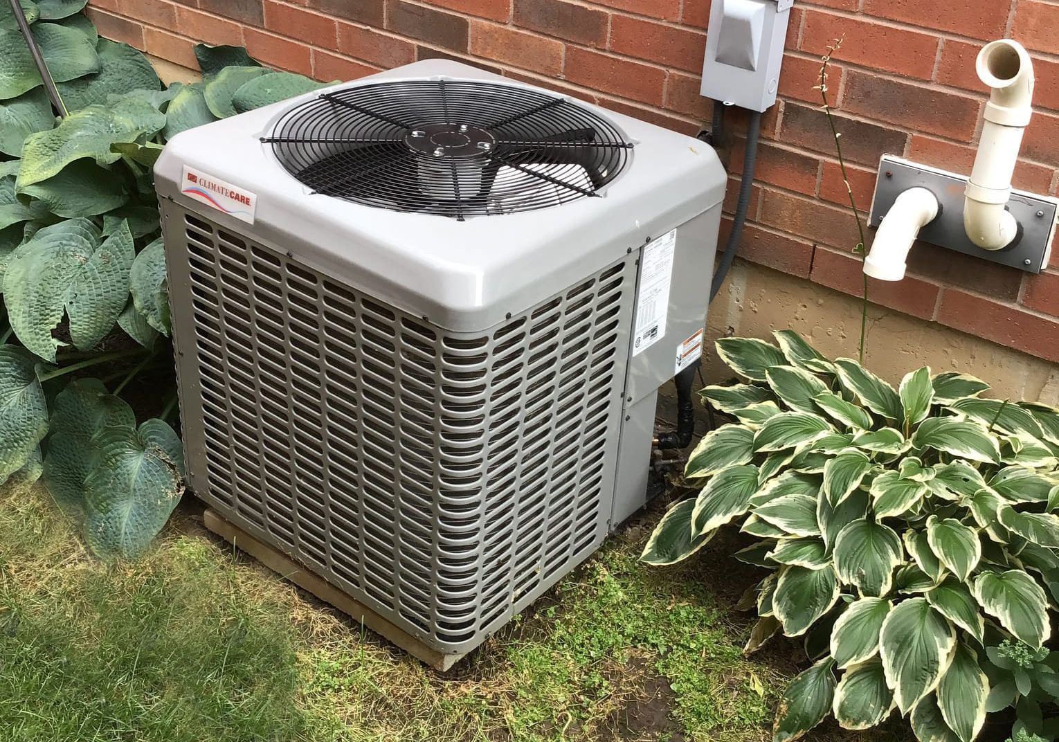 Outdoor central air conditioner condenser unit beside a house in Pickering, Ontario, ready for spring startup