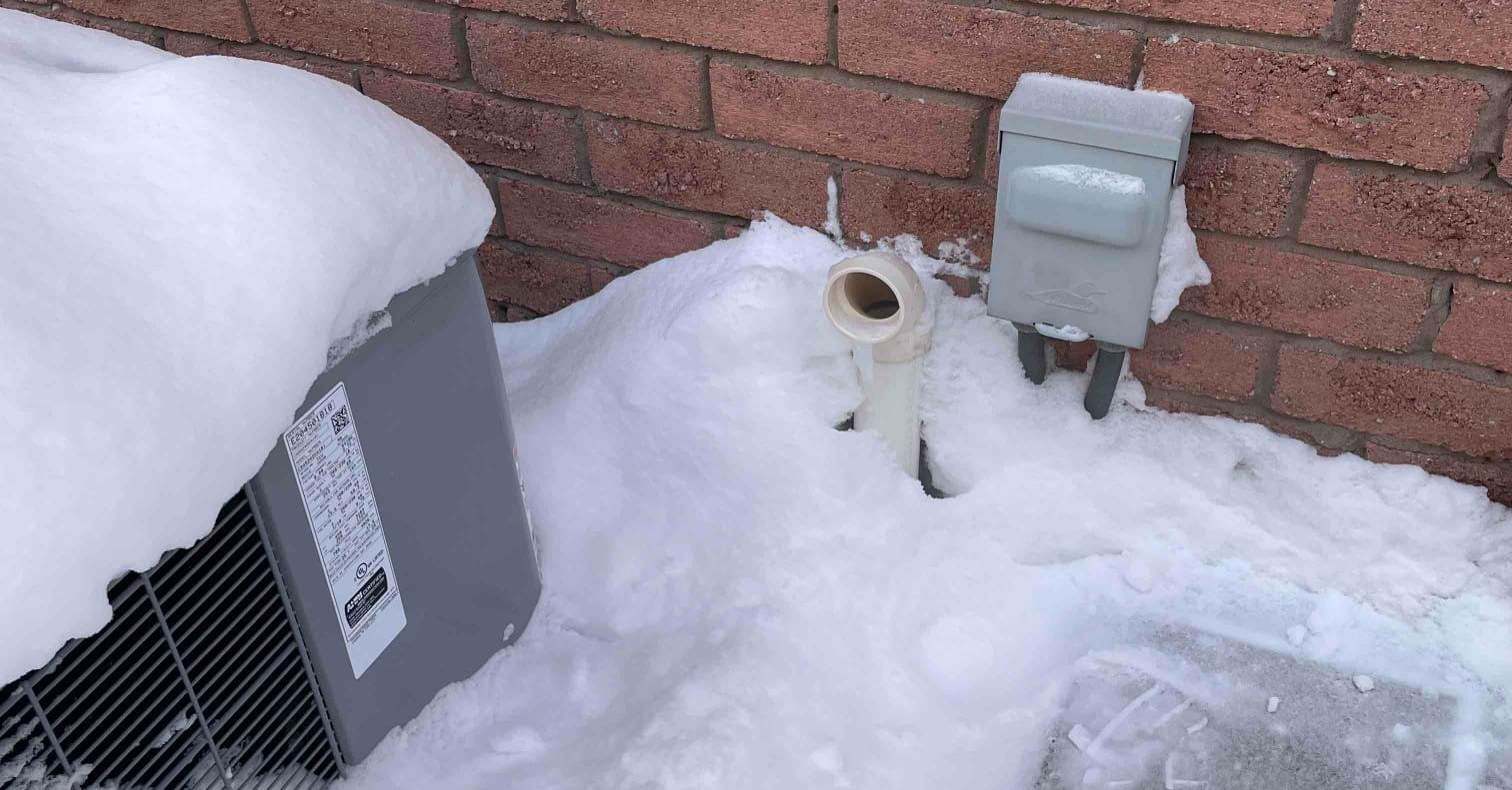 Blocked furnace exhaust vent covered by snow and ice outside a home after a snowstorm