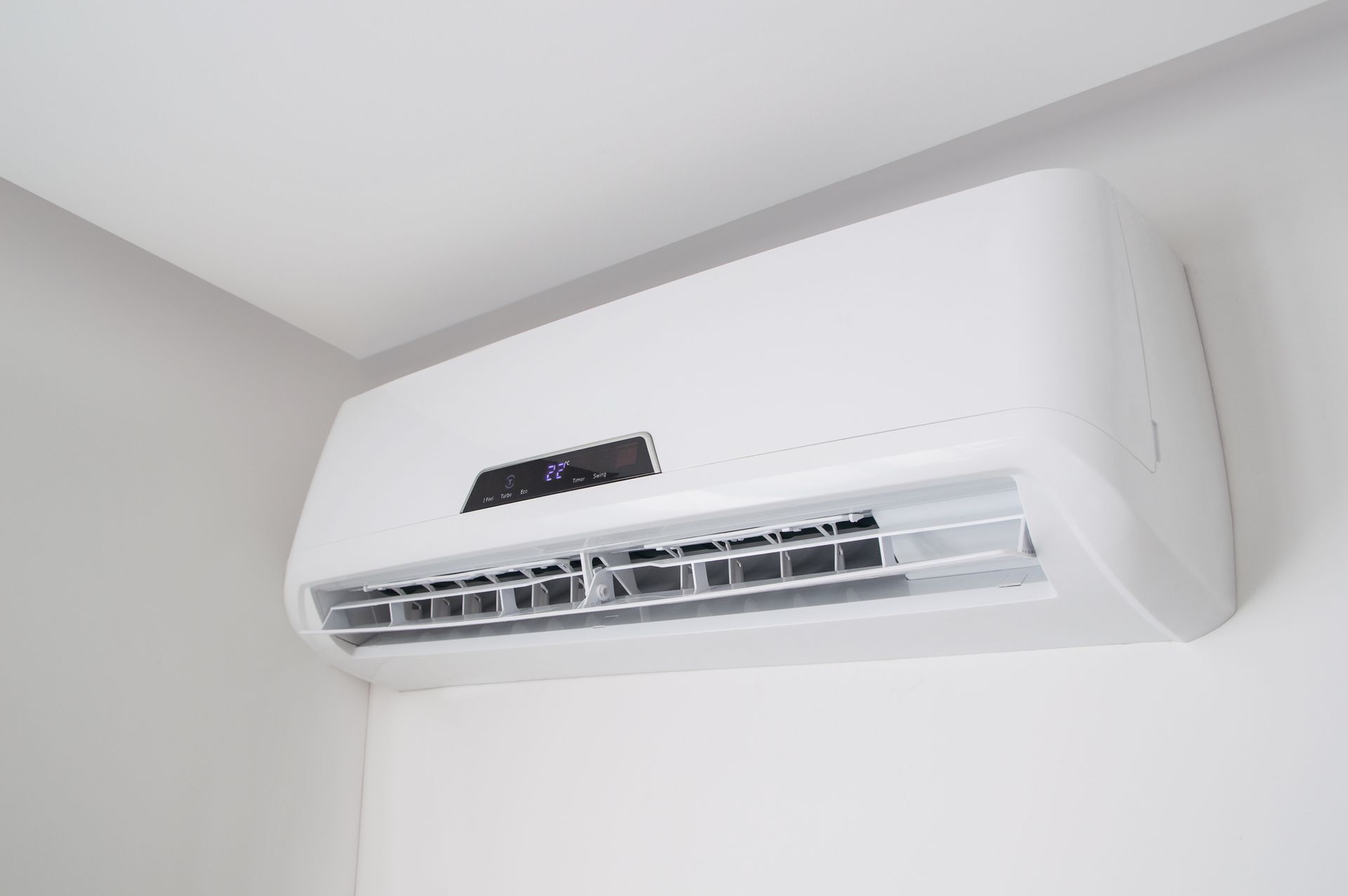 A white air conditioner is hanging from the ceiling in a room.