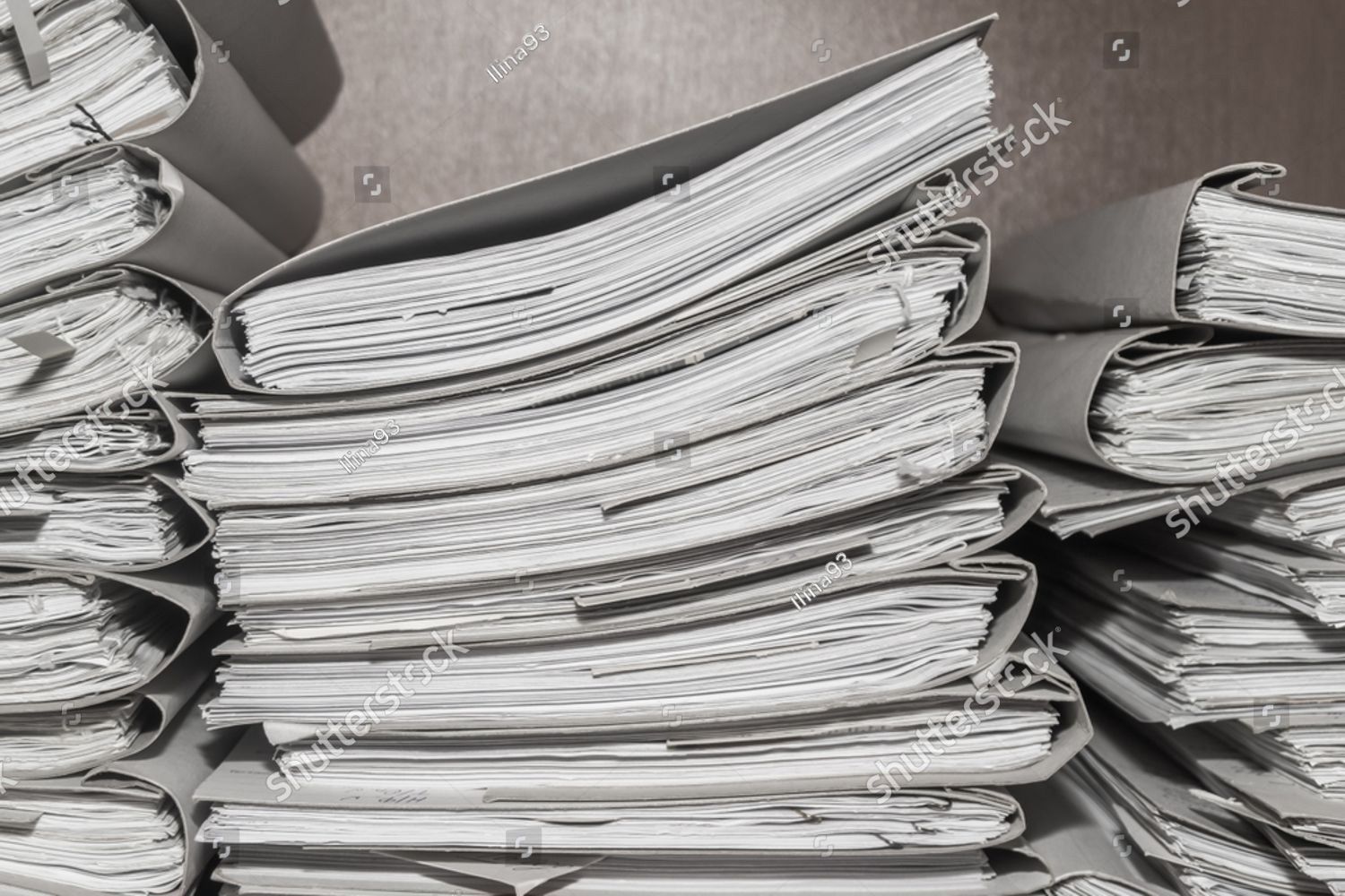 Stack of thick, open files on a desk, possibly in an office setting.