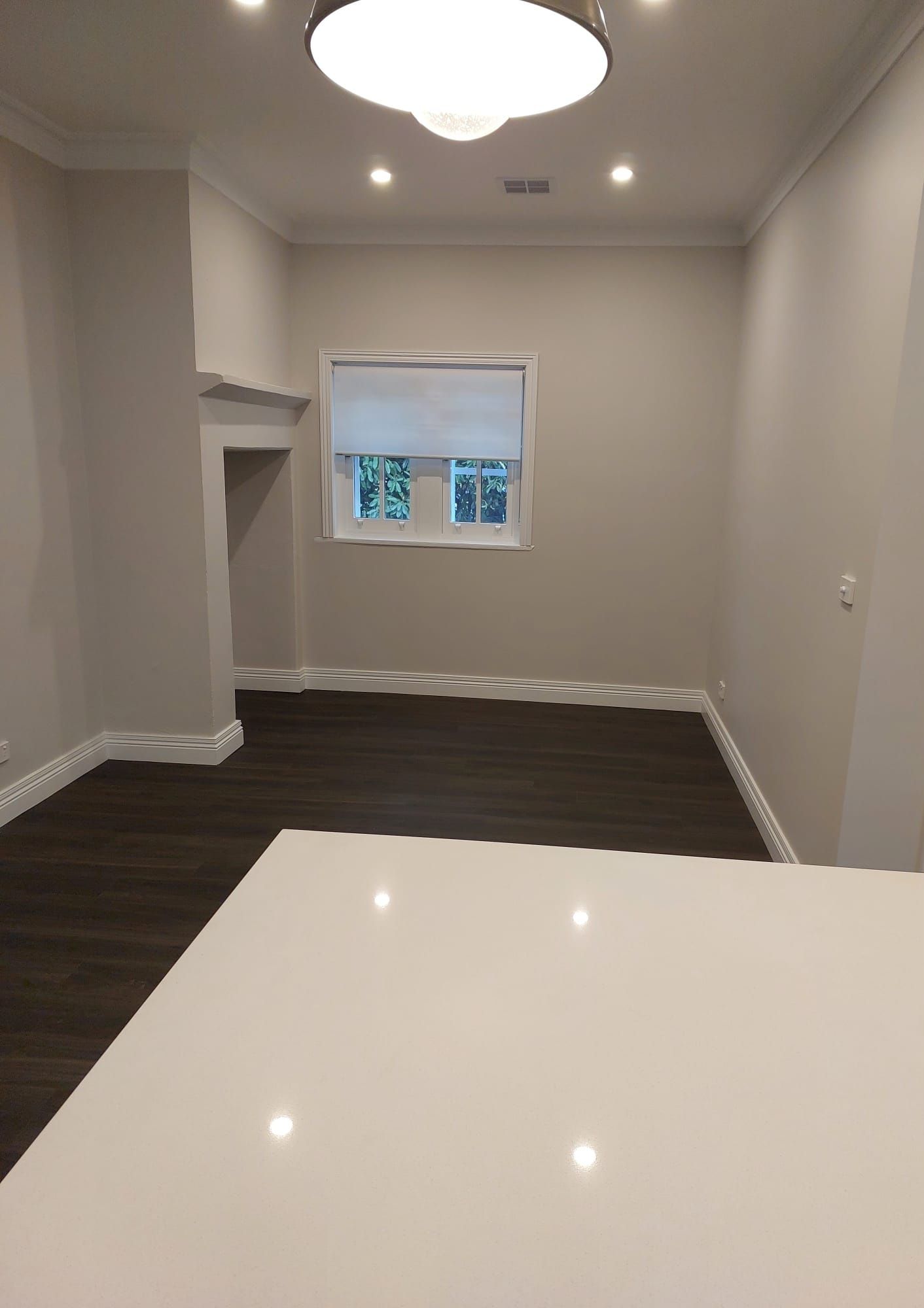 Empty Room With Dark Wood Floor, Light Gray Walls, White Trim, and a White Countertop in the Foreground  — Elimar Construction in Goulburn, NSW