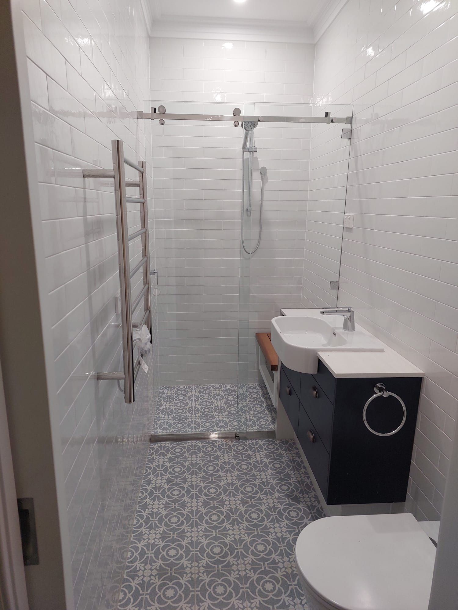 Modern Bathroom With White and Patterned Tile, Glass Shower, Vanity, and Toilet  — Elimar Construction in Goulburn, NSW
