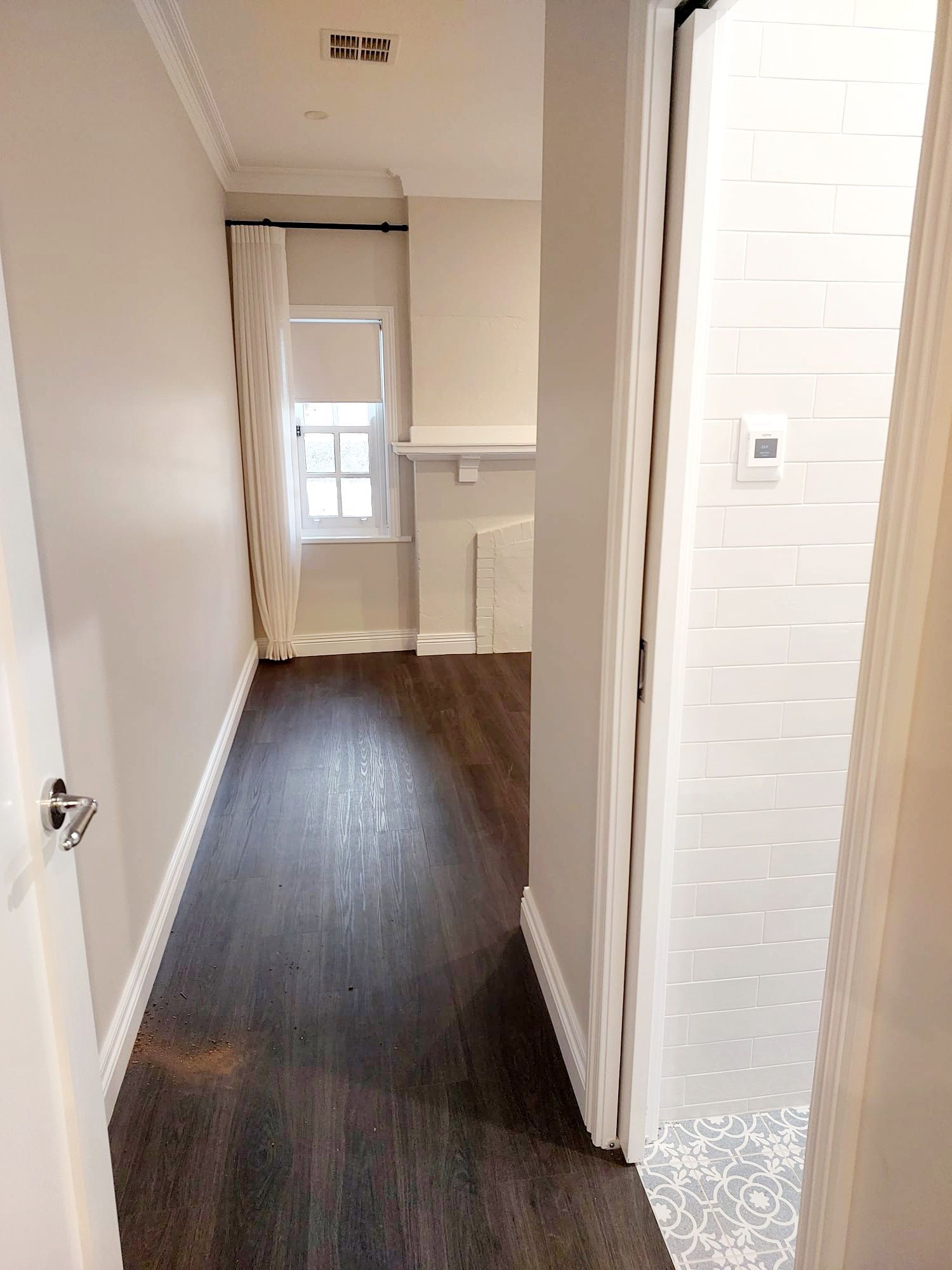 Narrow Hallway With Dark Wood Floor, Light Walls, and a Doorway to a Tiled Bathroom  — Elimar Construction in Goulburn, NSW