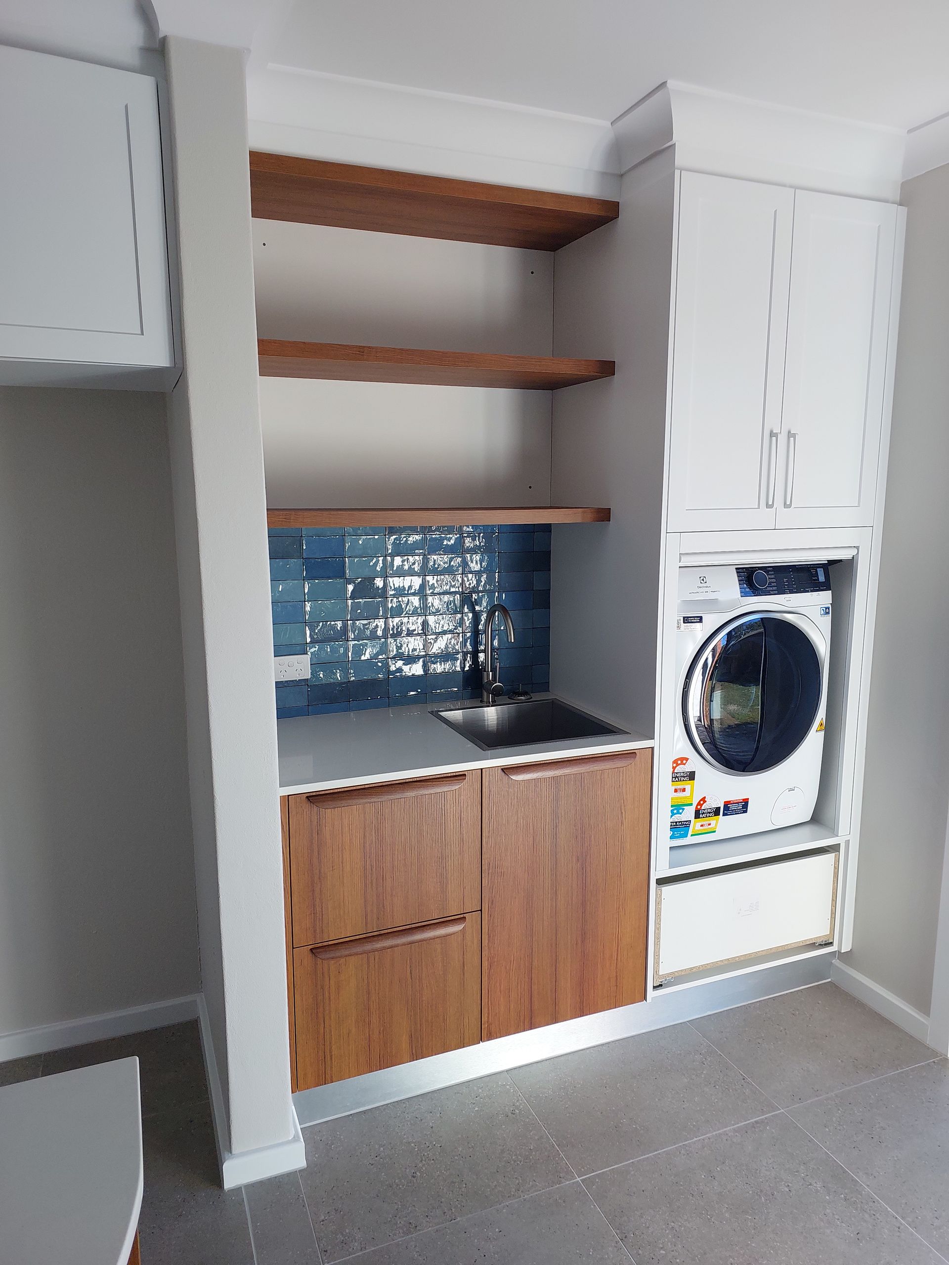 Laundry Room With Wooden Cabinets, Open Shelving, Blue Tiled Backsplash, and Washing Machine — Elimar Construction in Goulburn, NSW