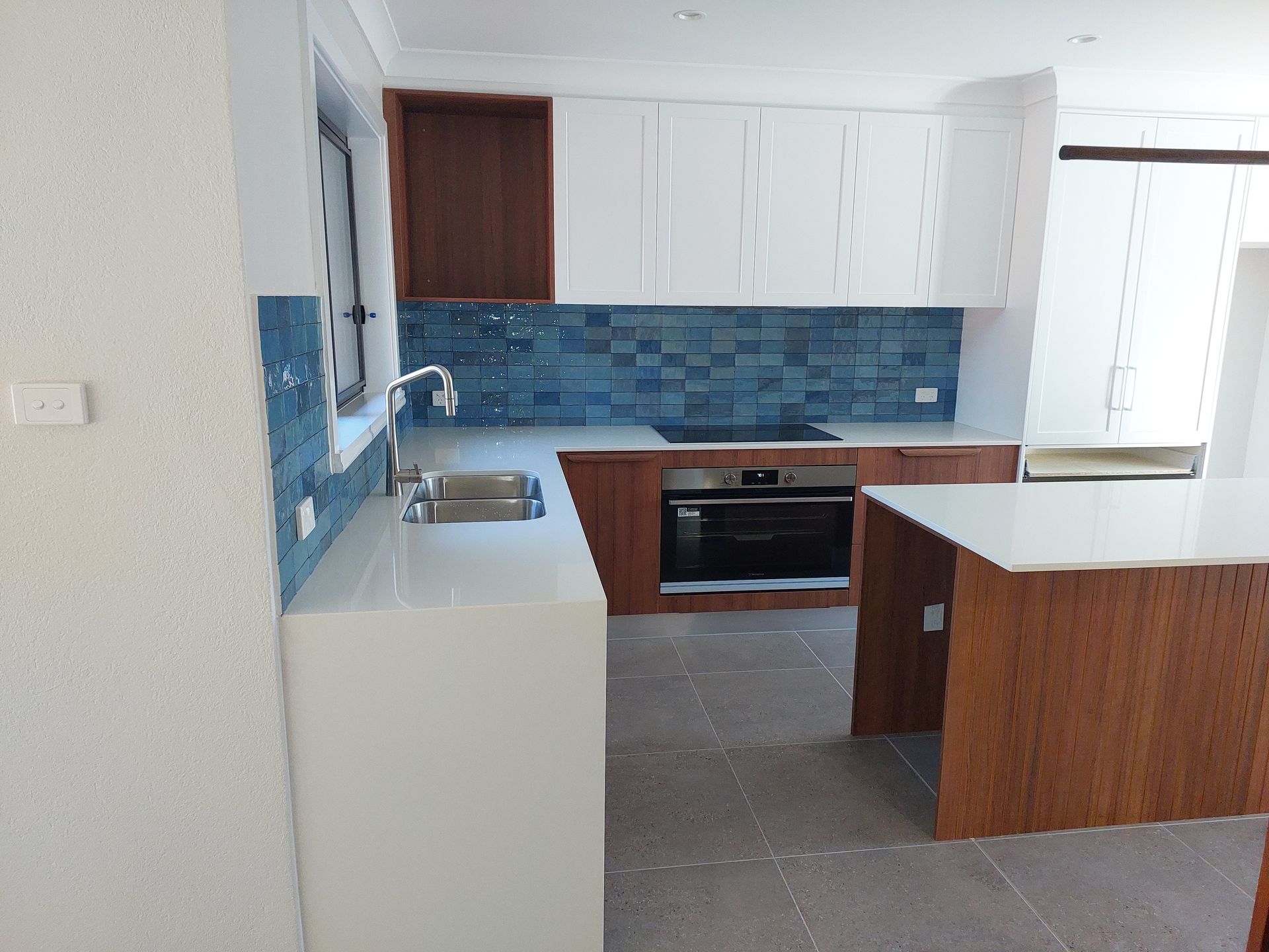 Modern Kitchen With White and Wood Cabinets, Blue Tile Backsplash, Stainless Steel Appliances, and Island — Elimar Construction in Goulburn, NSW