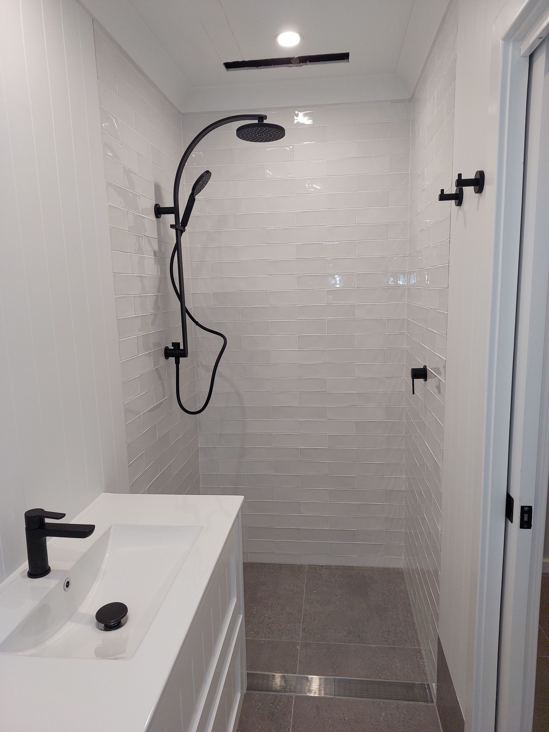 Modern Bathroom With White Sink, Black Fixtures, and Tiled Shower — Elimar Construction in Goulburn, NSW