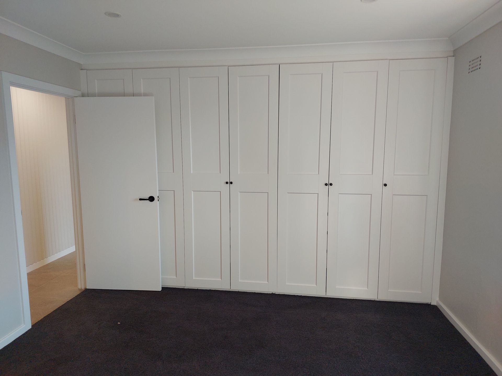 White Wardrobe Covers Most of a Bedroom Wall; a White Door is on the Left — Elimar Construction in Goulburn, NSW