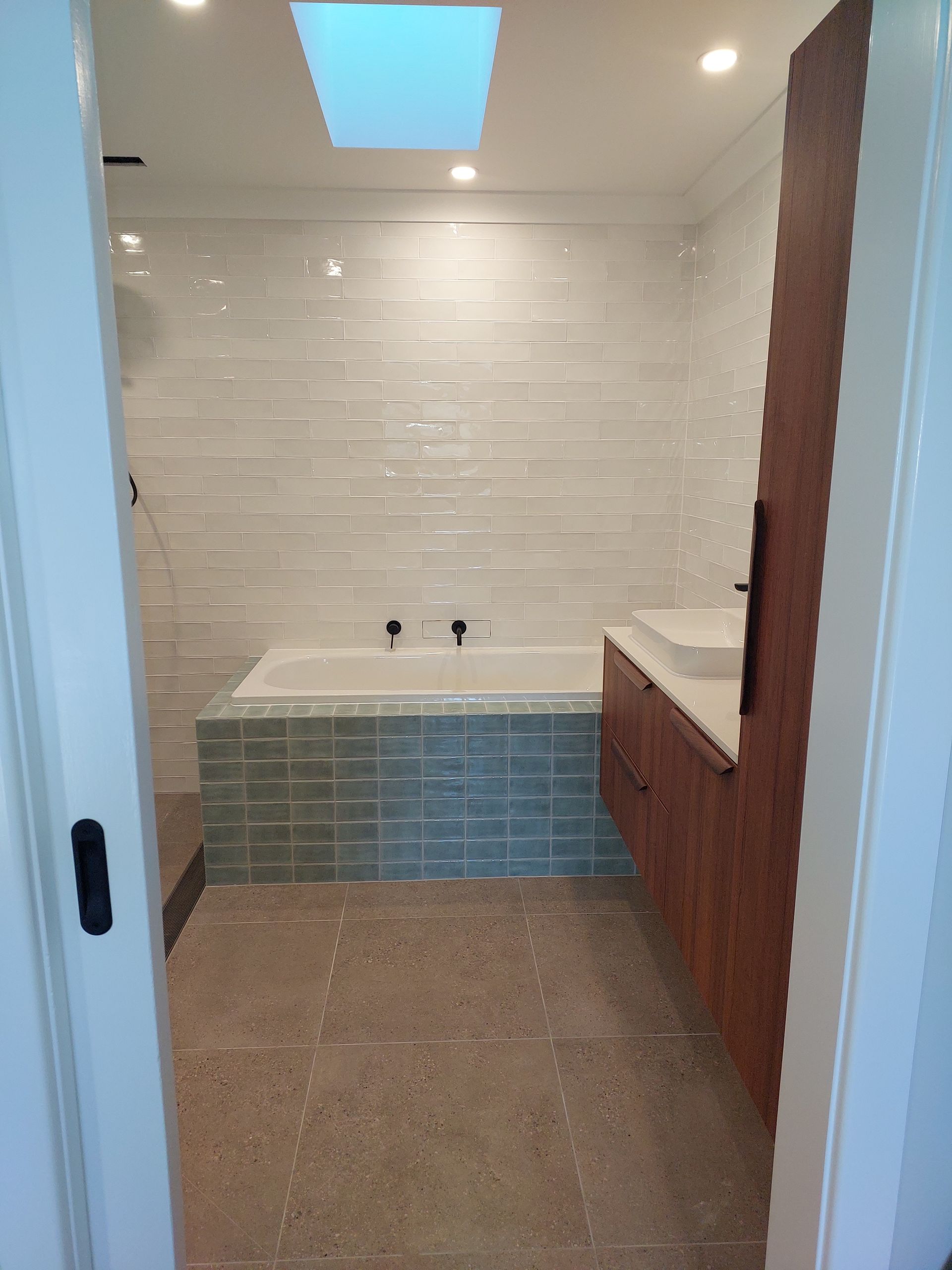 Bathroom With White and Teal Tiles, a Skylight, a Wooden Vanity, and a Tub — Elimar Construction in Goulburn, NSW