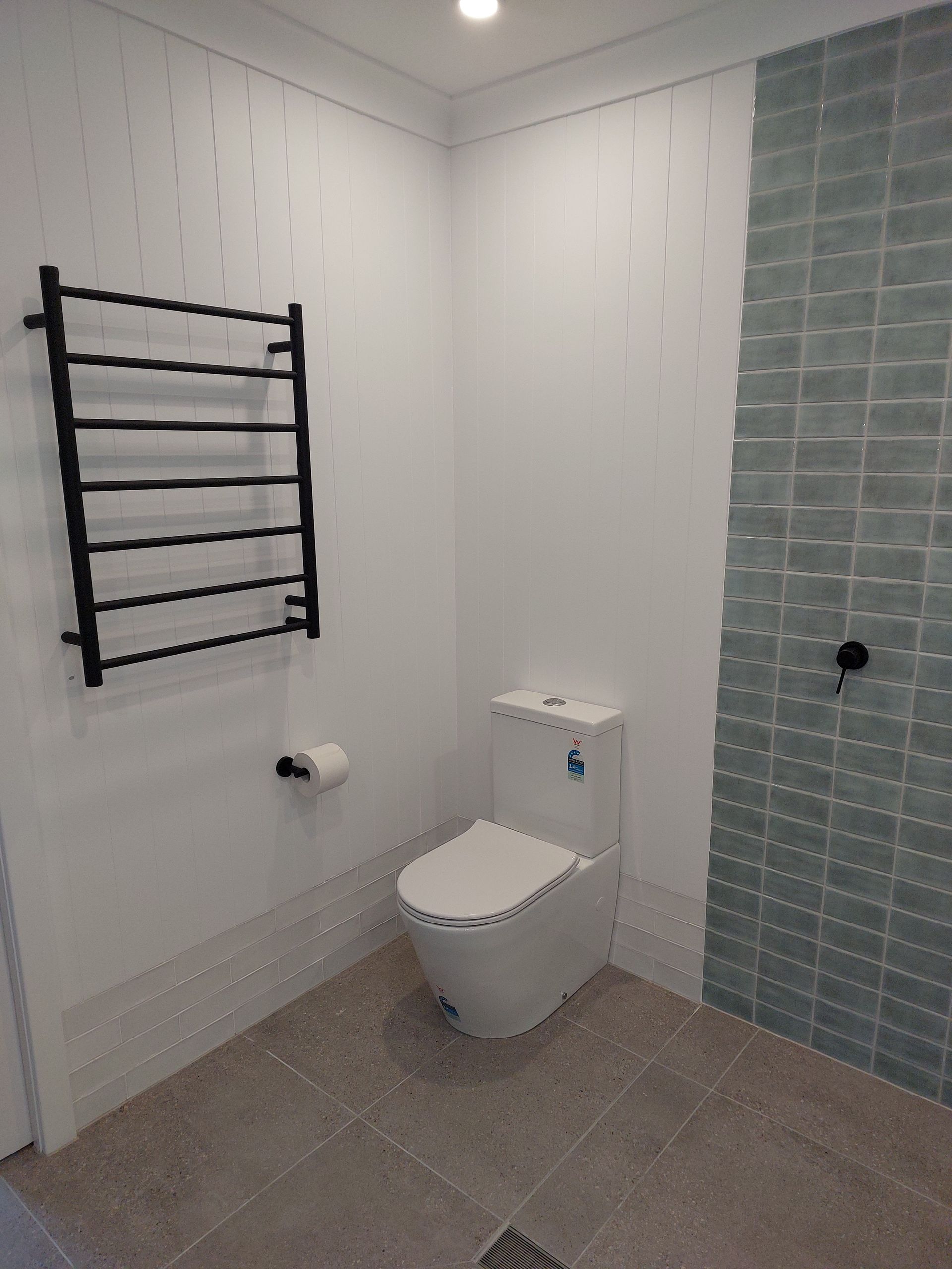 Bathroom With a White Toilet, Black Towel Rack, and Blue Tiled Shower — Elimar Construction in Goulburn, NSW