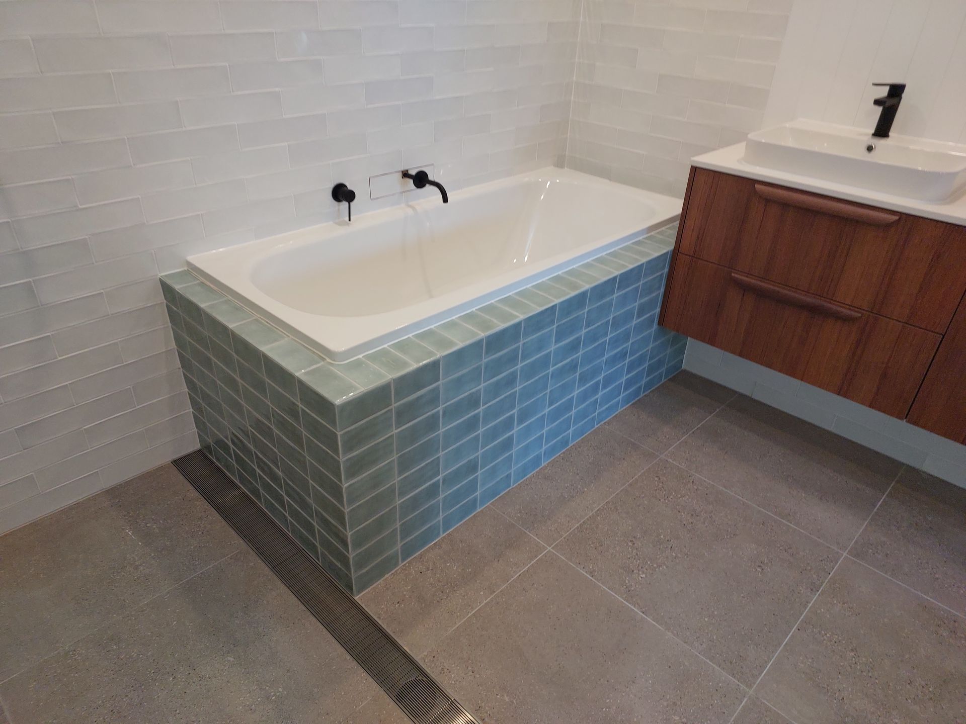 Bathroom With a White Bathtub and Teal Tile Base, Next to a Wooden Vanity — Elimar Construction in Goulburn, NSW