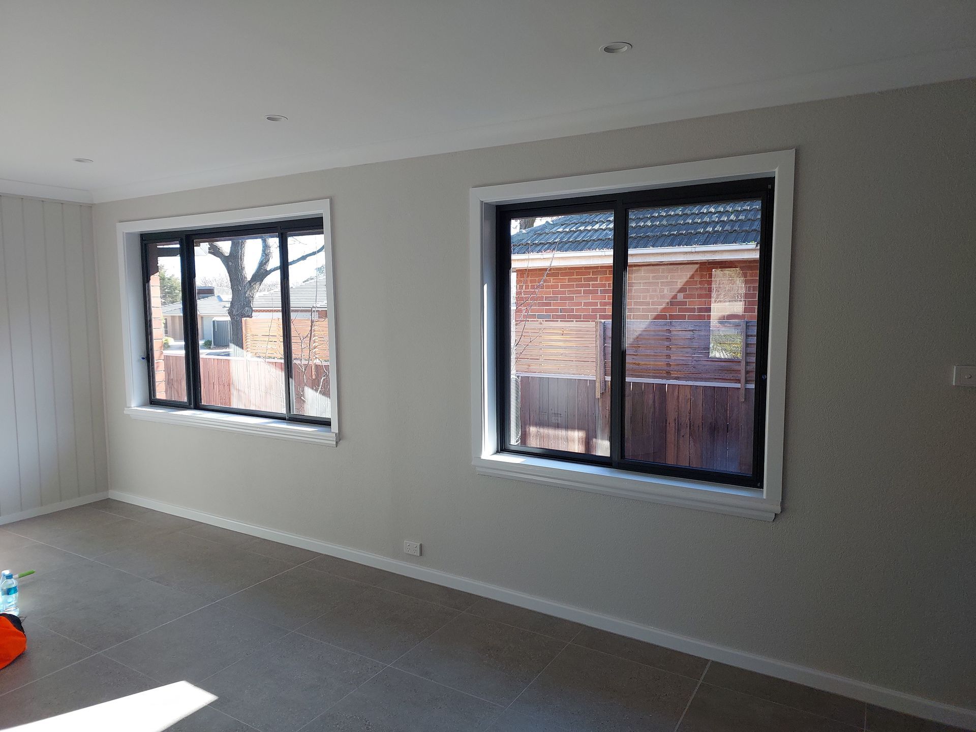 Two Windows With Black Frames in a Room With Gray Walls and a Tile Floor. Outside View — Elimar Construction in Goulburn, NSW