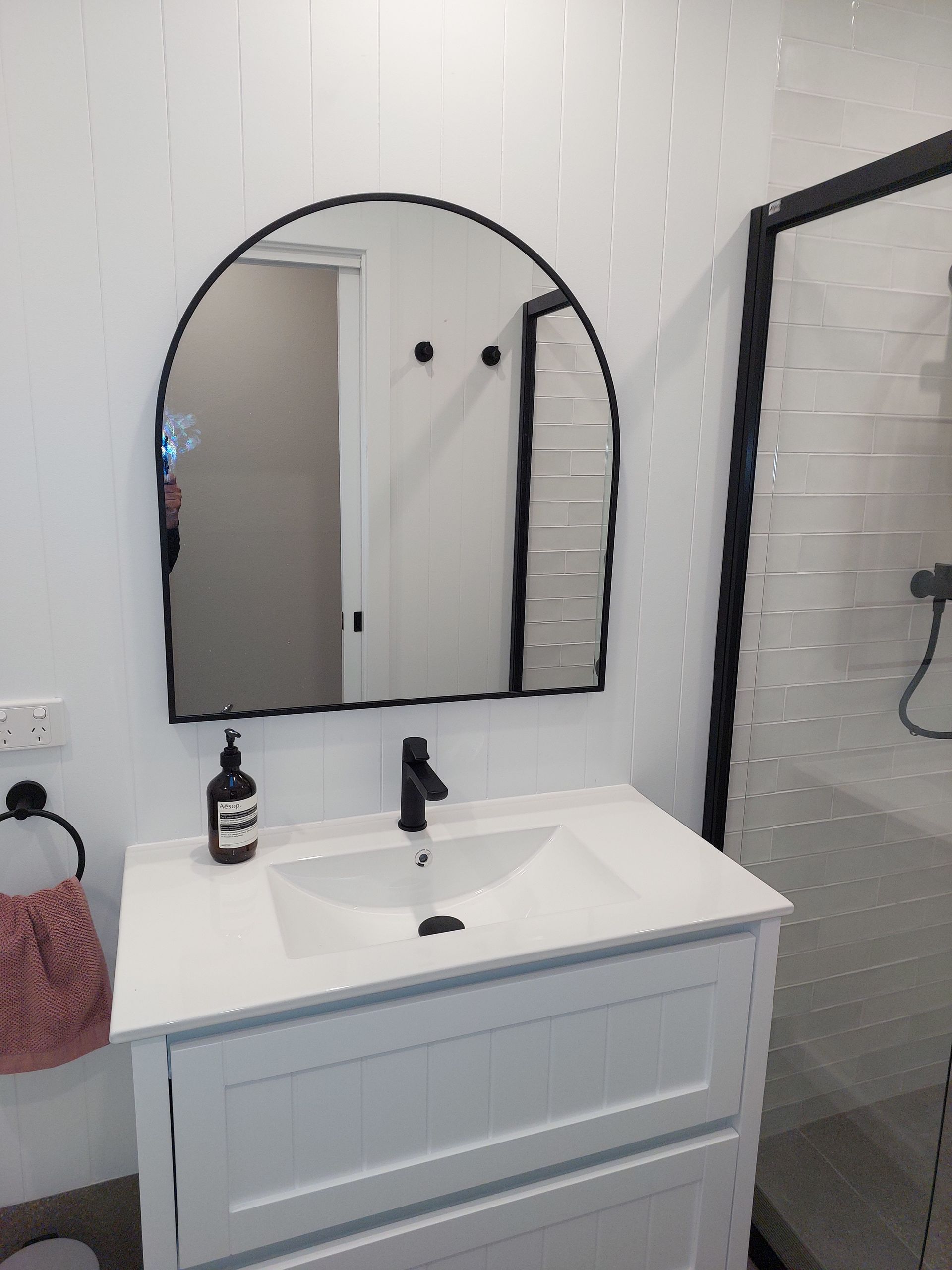 White Bathroom Vanity With Arched Black Mirror, Black Faucet, and Shower Enclosure — Elimar Construction in Goulburn, NSW
