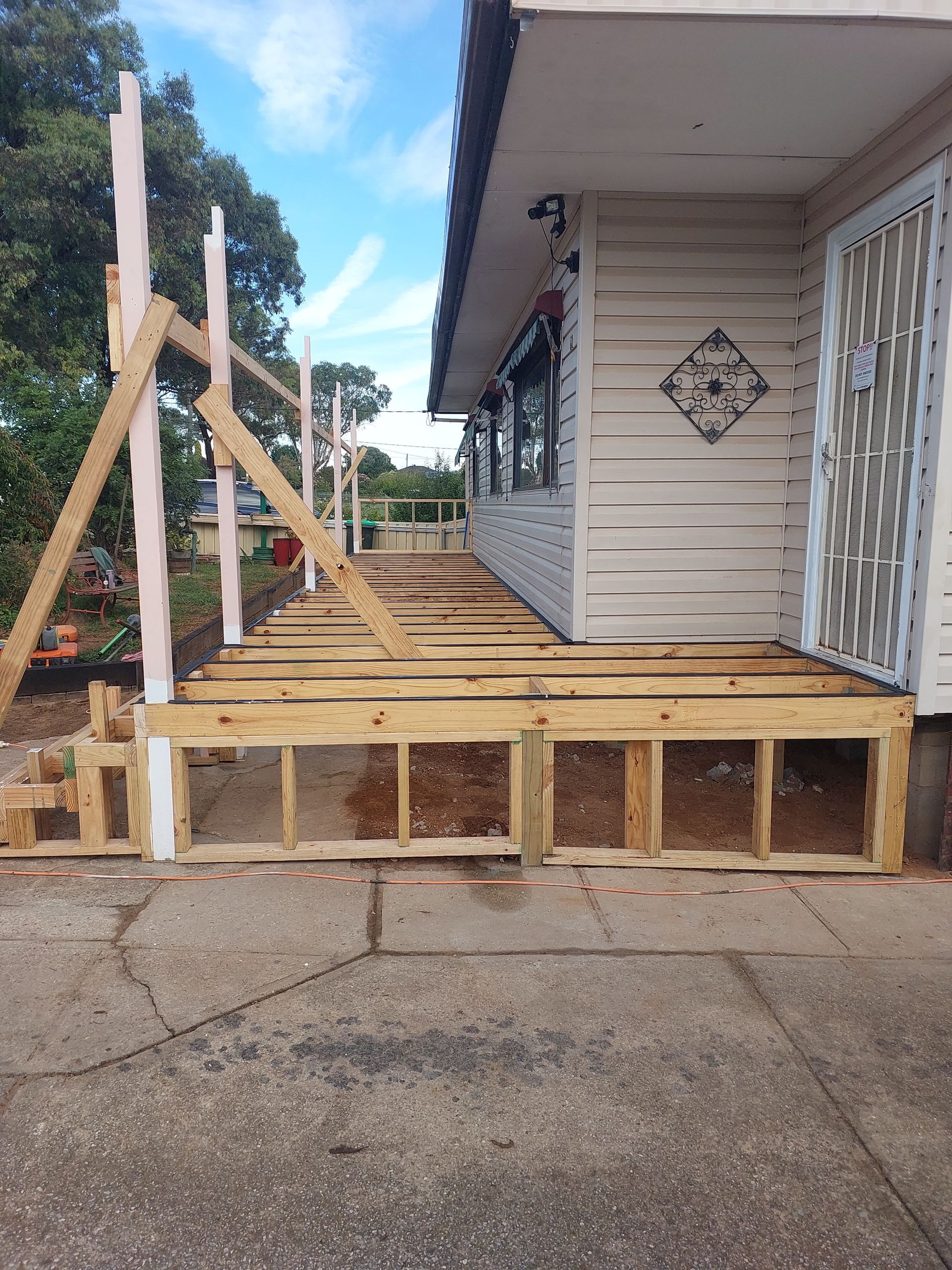 A Wooden Deck is Being Built on the Side of a House — Elimar Construction in Goulburn, NSW