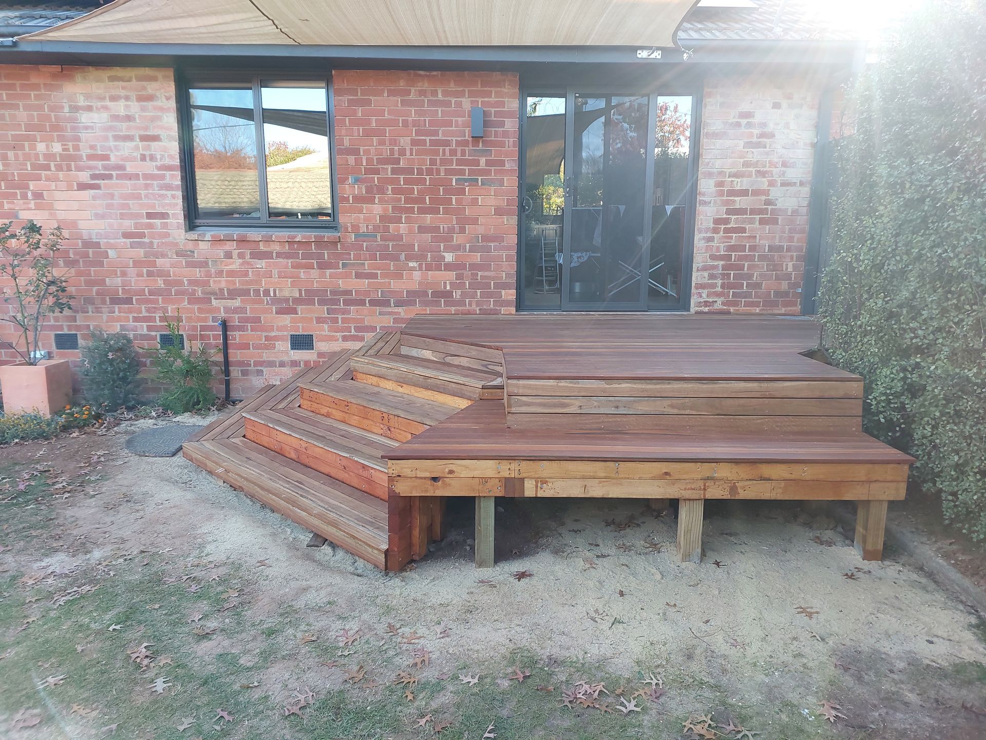 Wooden Deck With Steps Against a Brick House, Partially Shaded by a Beige Canopy — Elimar Construction in Goulburn, NSW