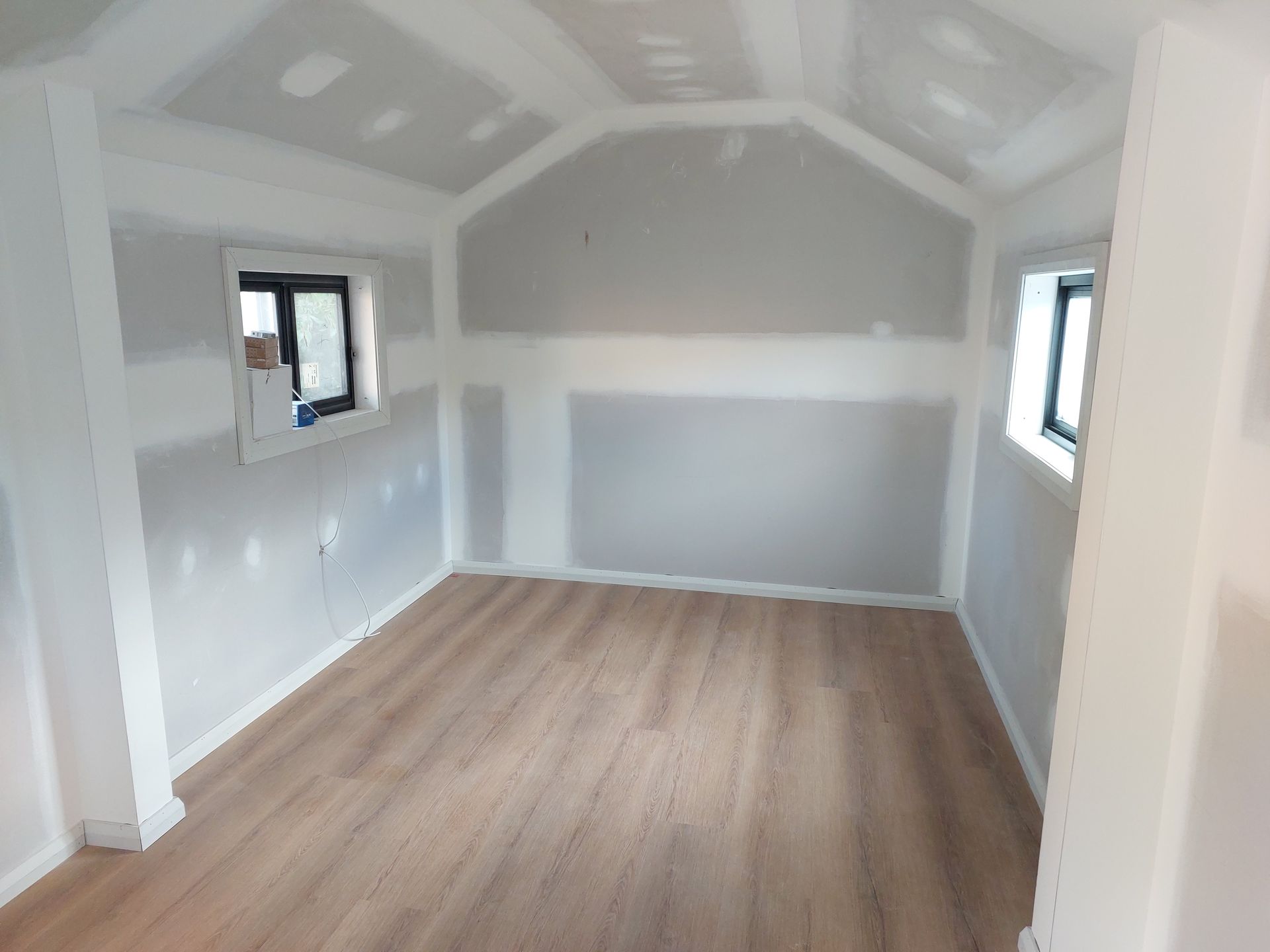 Interior of a Small Room Under Construction, With Wood Flooring, Drywall Walls, and Two Windows — Elimar Construction in Goulburn, NSW