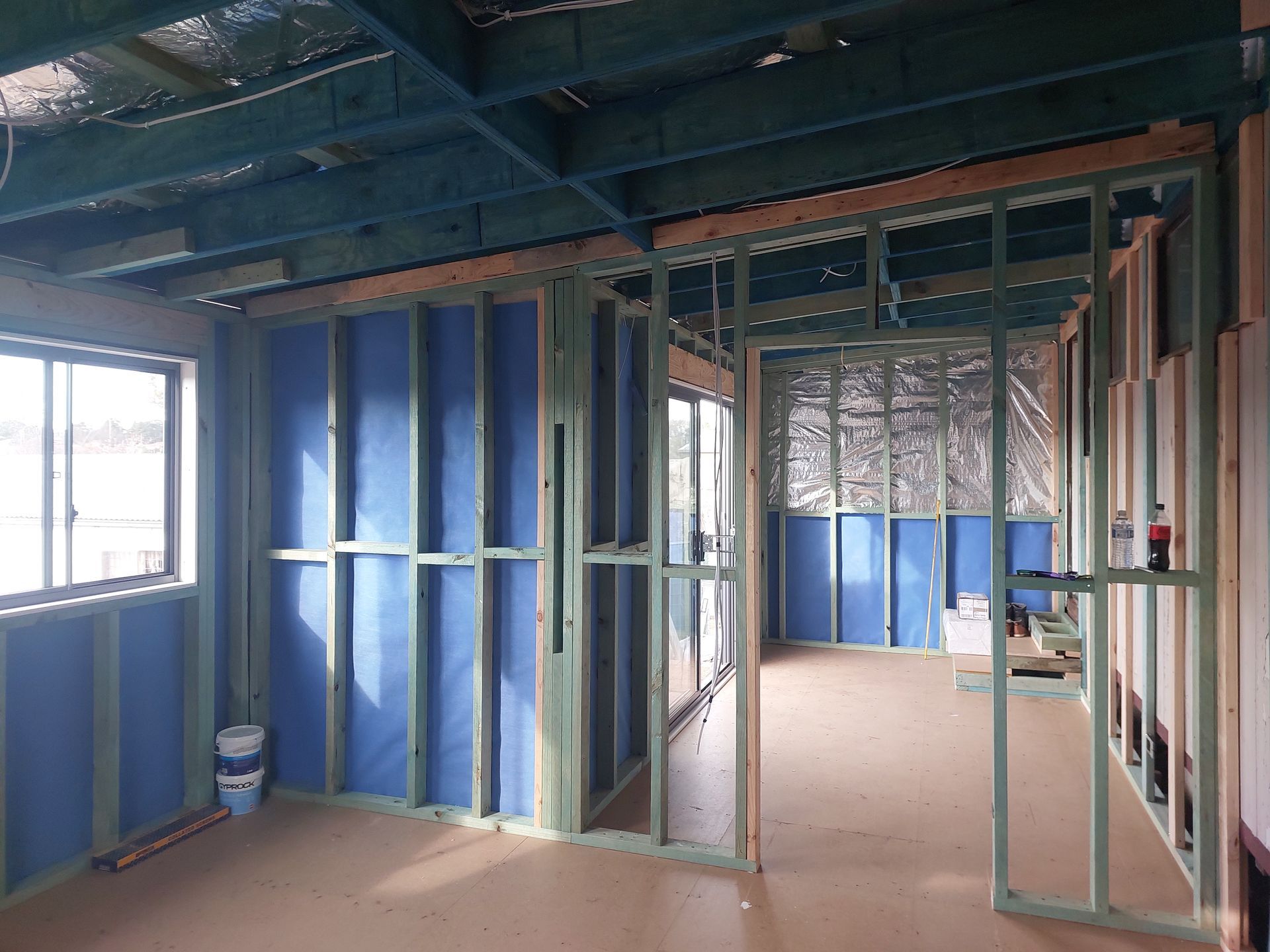 Interior View of a Building Under Construction, Showing Wooden Frames, Blue Insulation, and a Window — Elimar Construction in Goulburn, NSW