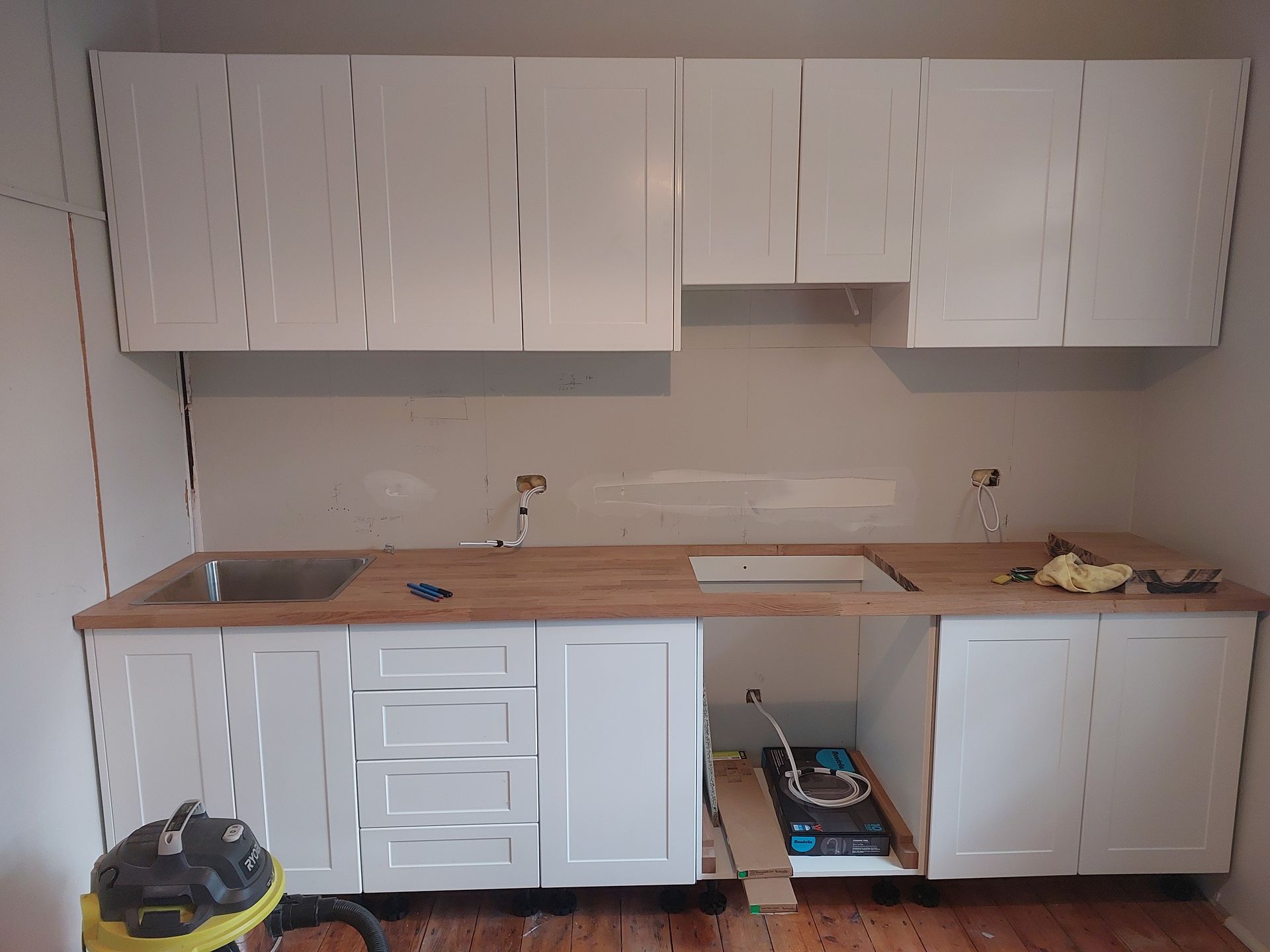 A Kitchen With White Cabinets and a Yellow Vacuum Cleaner — Elimar Construction in Goulburn, NSW