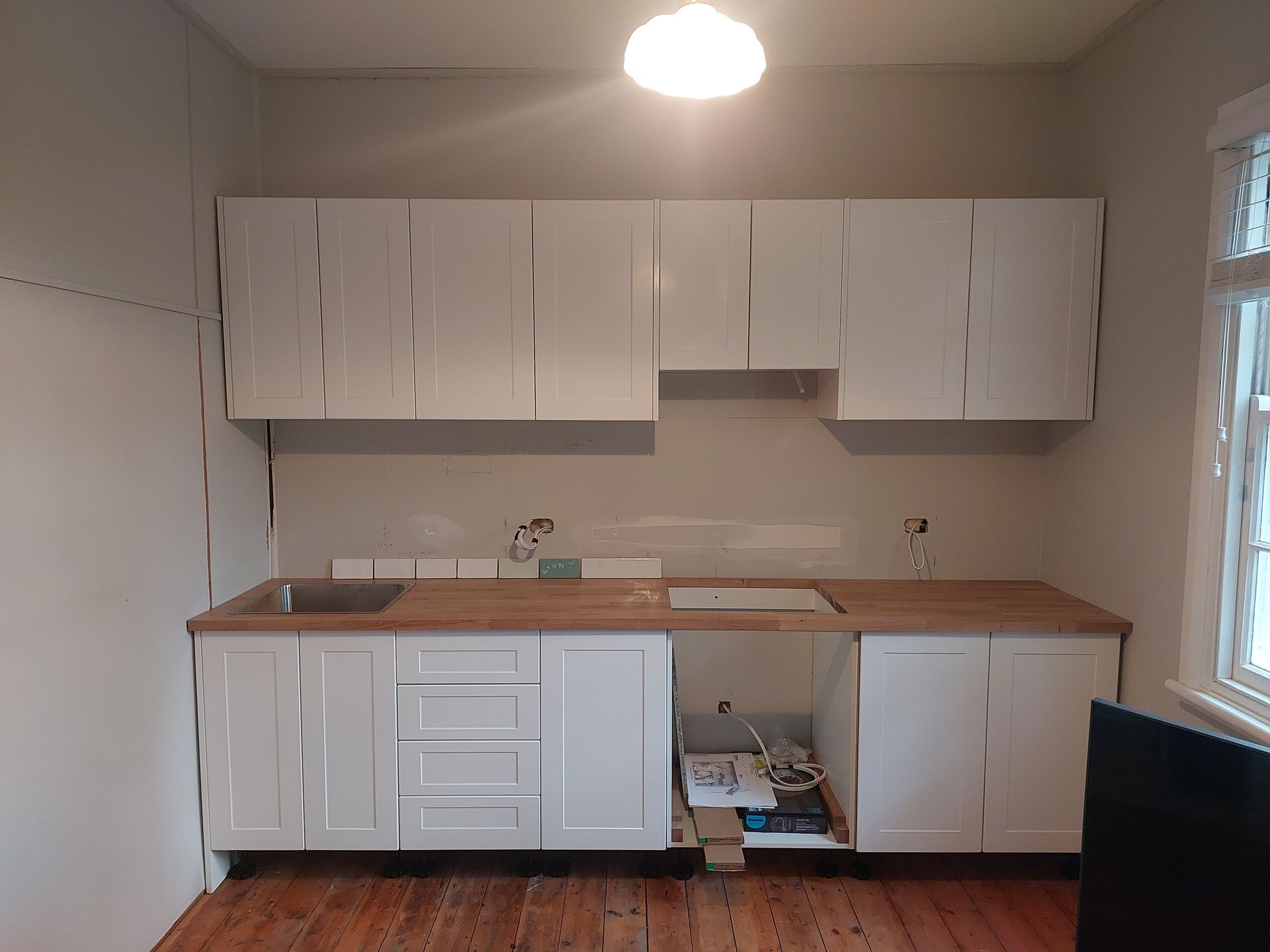 A Kitchen With White Cabinets and a Wooden Counter Top — Elimar Construction in Goulburn, NSW