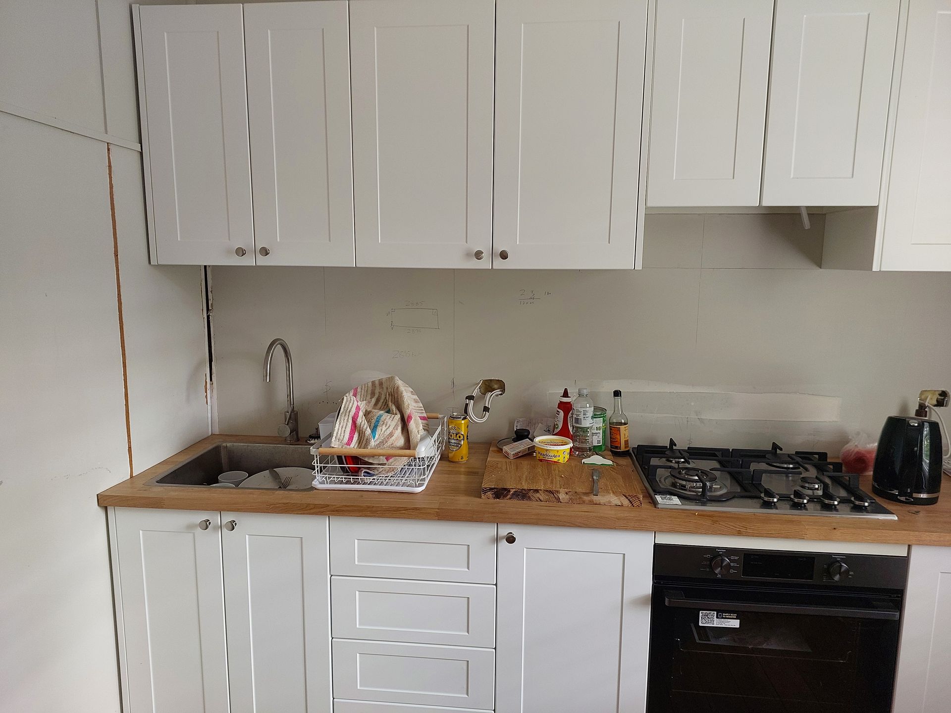A Kitchen With White Cabinets, a Sink, a Stove, and an Oven — Elimar Construction in Goulburn, NSW