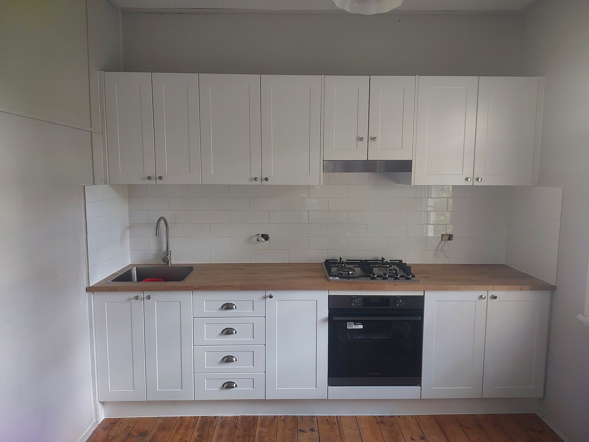 A Kitchen With White Cabinets and Wooden Counter Tops  — Elimar Construction in Goulburn, NSW