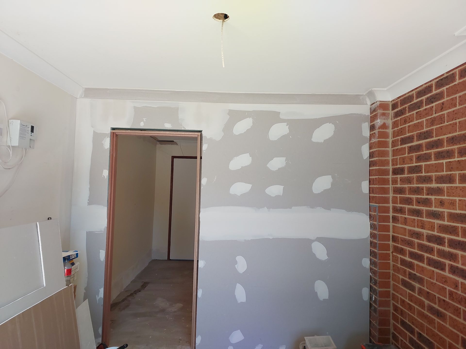 Room Under Construction With Exposed Brick Wall, Partially Installed Drywall, and Open Doorway — Elimar Construction in Goulburn, NSW