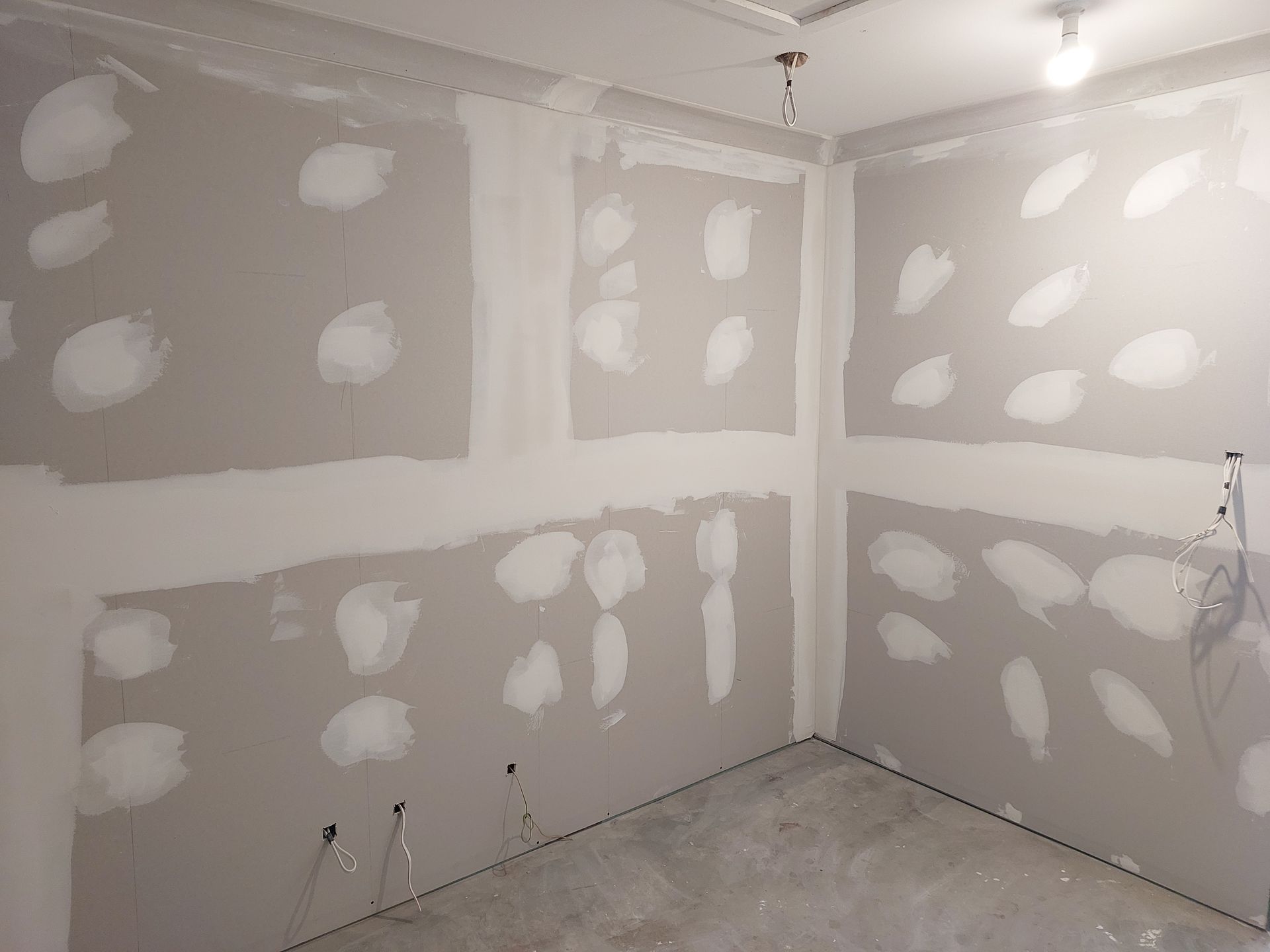 Interior of a Room With Drywall Installation, Showing Patches of Compound on Gray Walls and a Concrete Floor — Elimar Construction in Goulburn, NSW