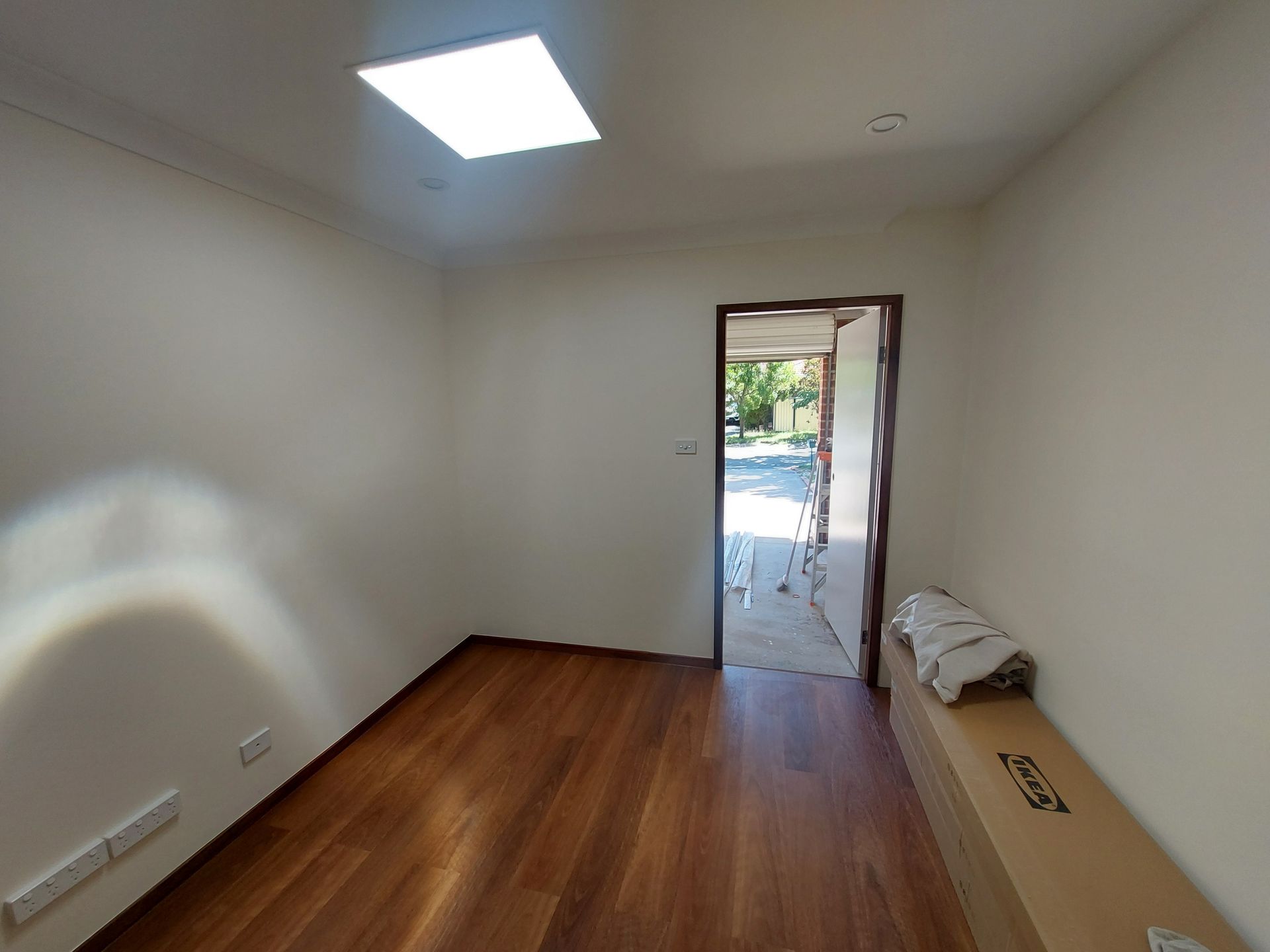 Empty Room With Wooden Floor, Door Open to Outside, Skylight, and Cardboard Box — Elimar Construction in Goulburn, NSW