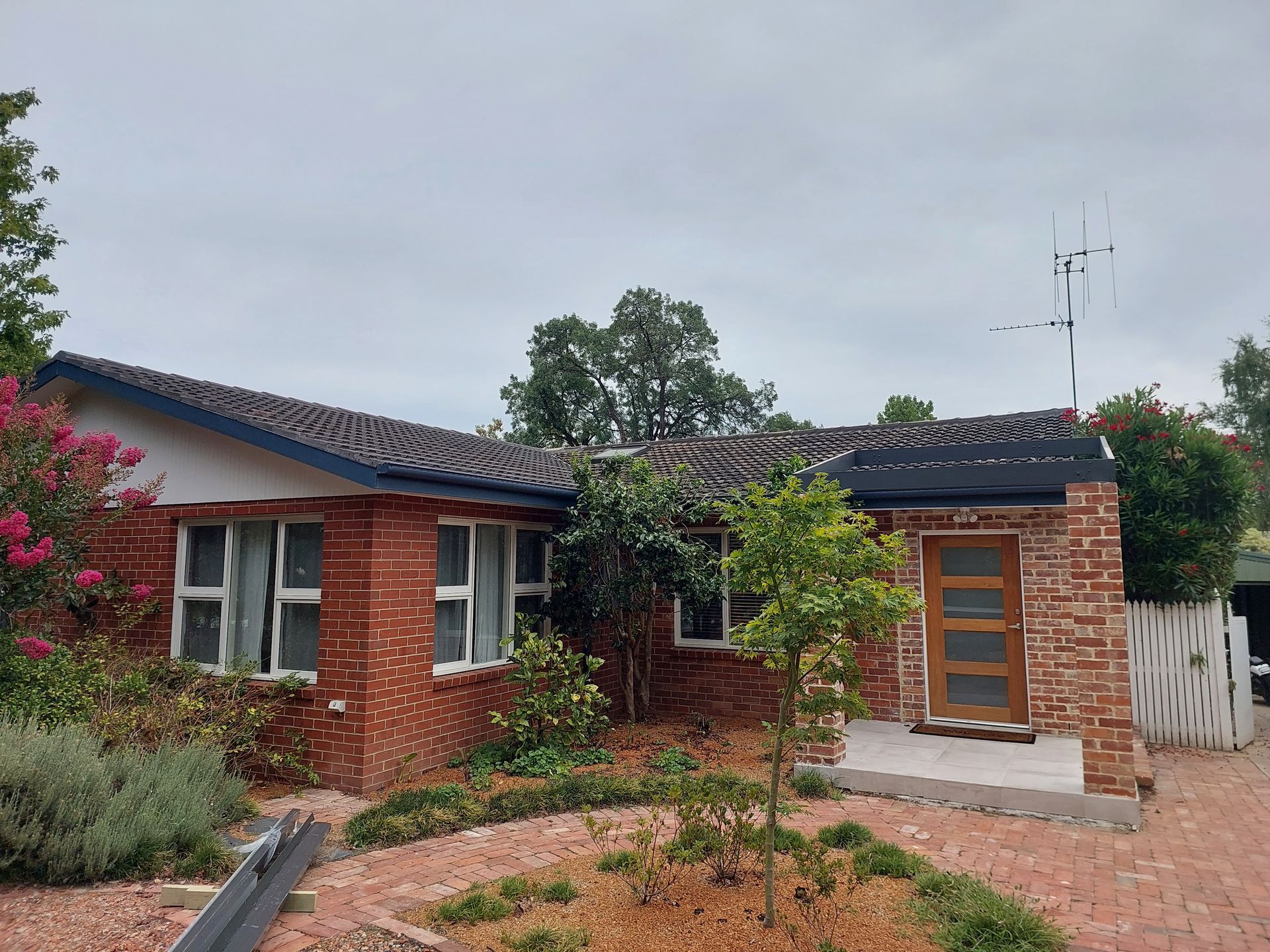 Red Brick House With Dark Roof, Small Front Yard With Shrubs, and a Cloudy Sky — Elimar Construction in Goulburn, NSW