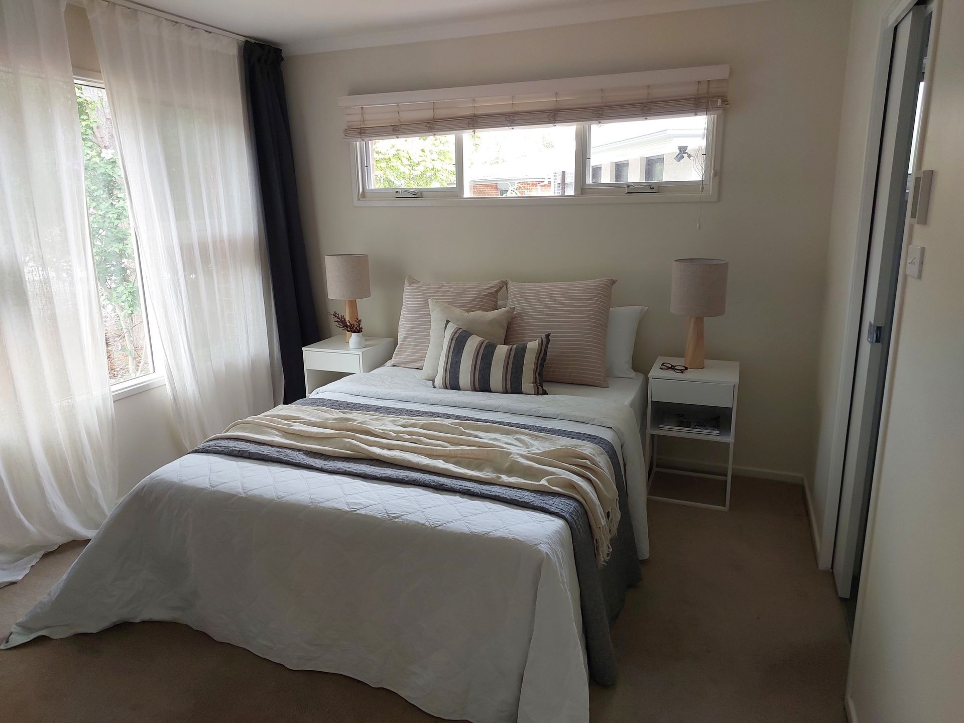 Bedroom With a Bed, Nightstands, Window With Curtains, and a Closed Door — Elimar Construction in Goulburn, NSW