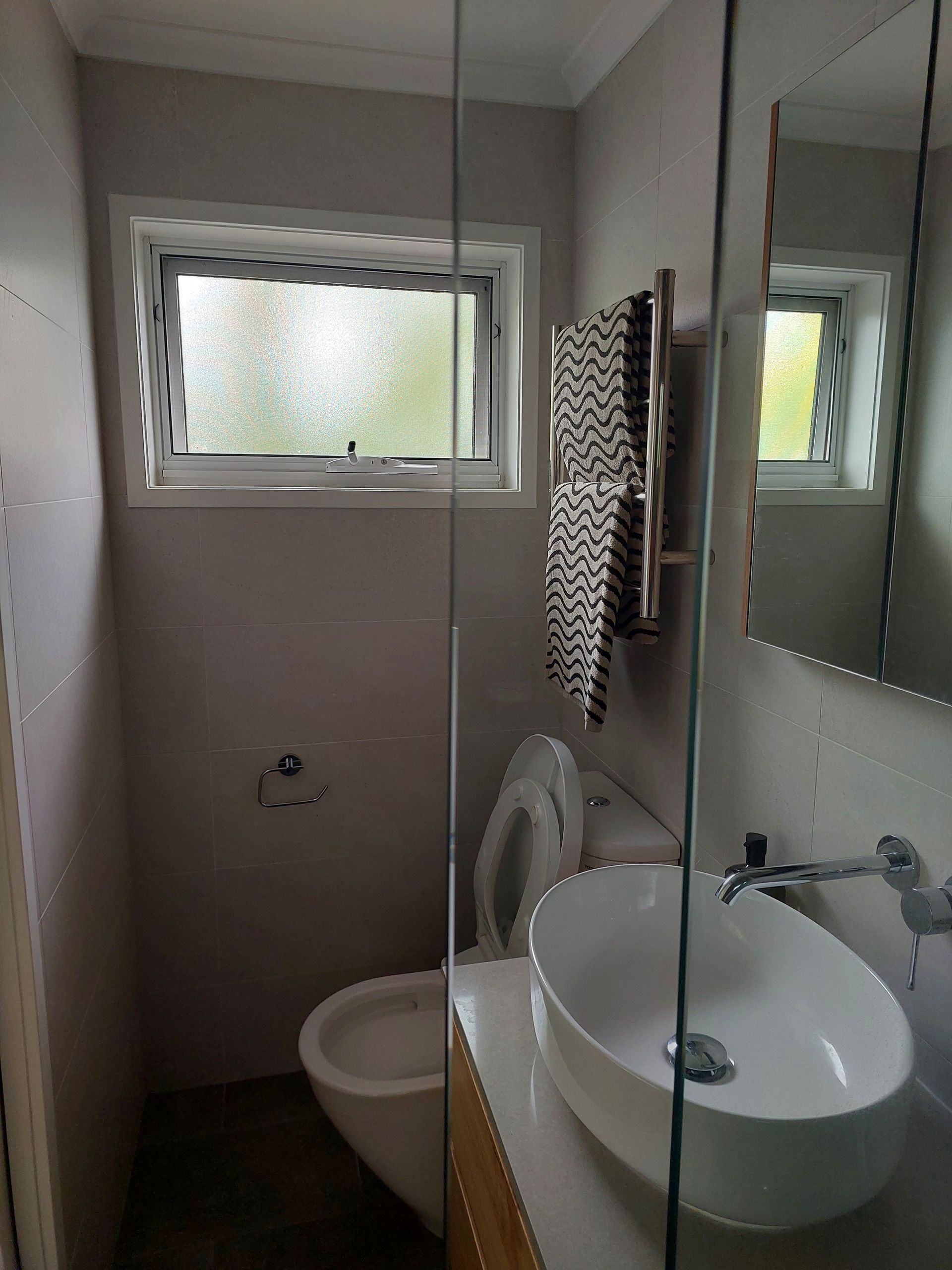 Small Bathroom With Toilet, Sink, Mirror, Window, and Towel Rack — Elimar Construction in Goulburn, NSW