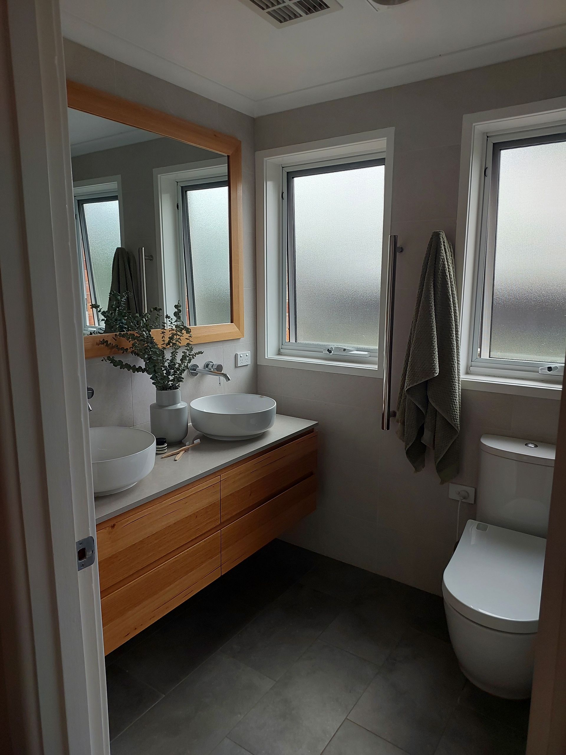 Bathroom With Wooden Vanity, Two White Vessel Sinks, and Frosted Windows — Elimar Construction in Goulburn, NSW
