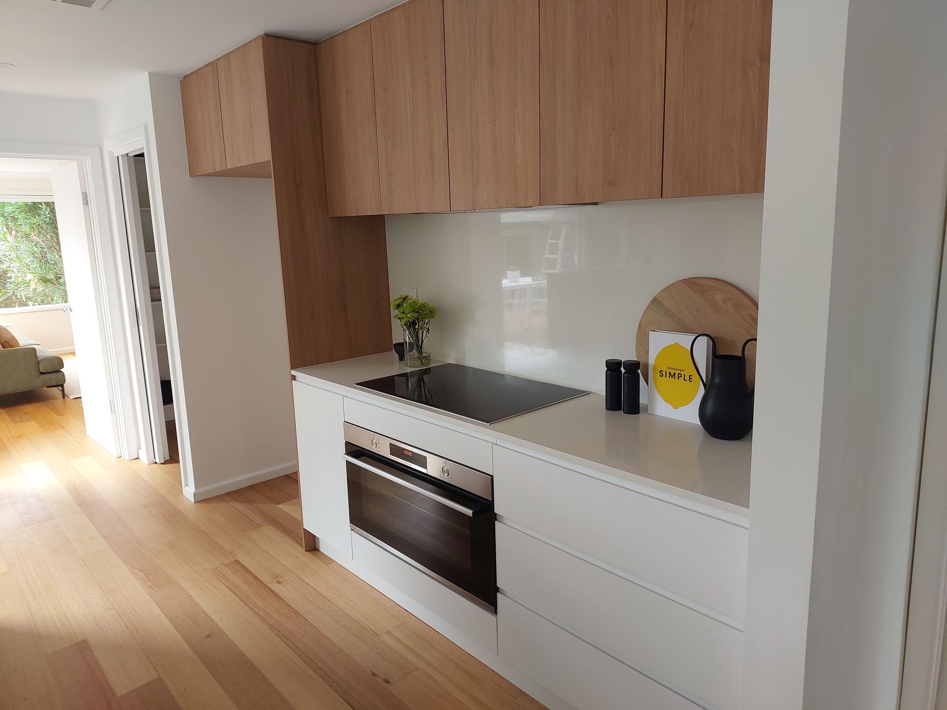 Modern Kitchen With White Countertops, Wooden Cabinets, and a Built-in Oven and Stovetop — Elimar Construction in Goulburn, NSW