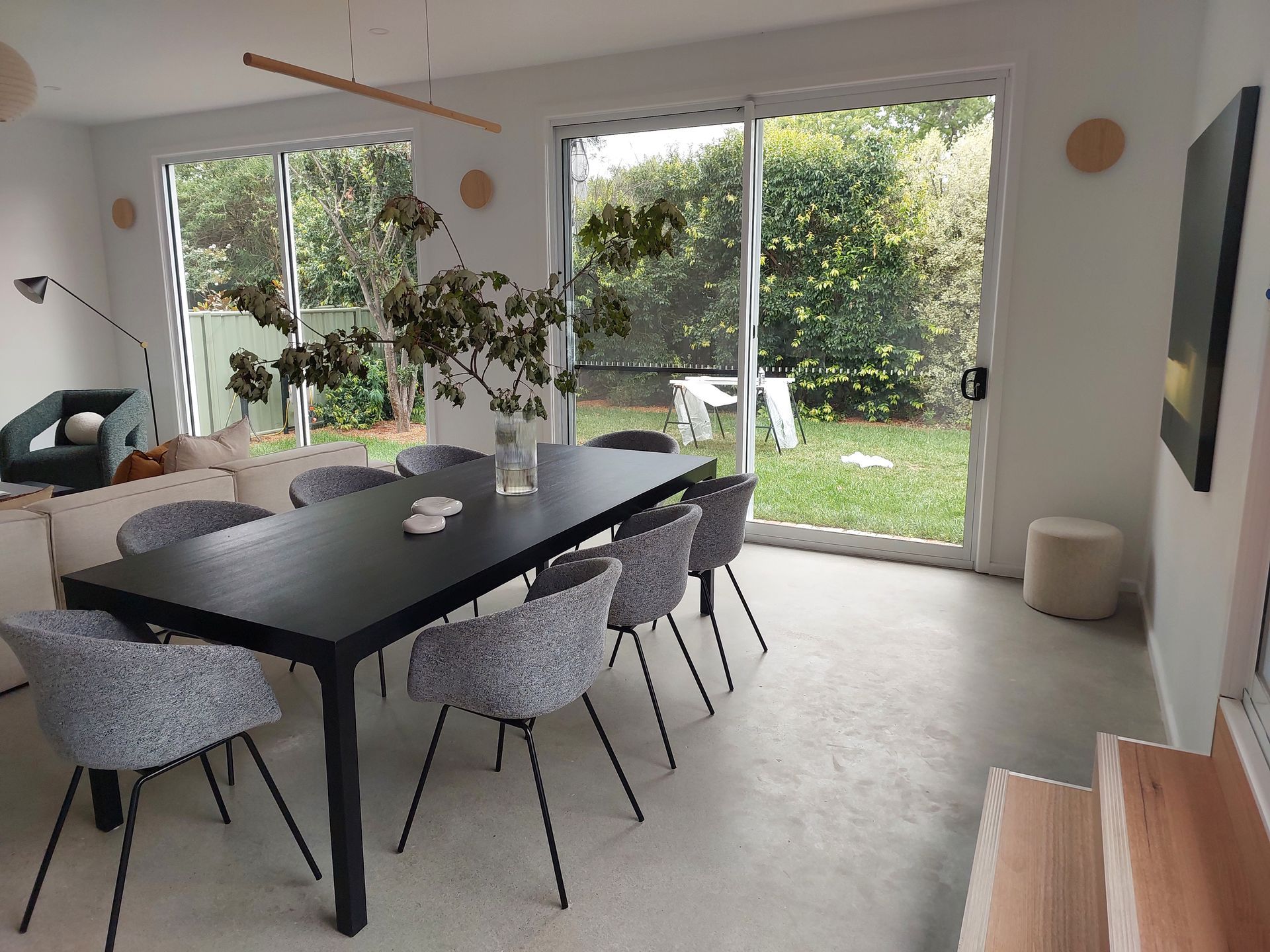 Dining Room With Black Table, Gray Chairs, Sliding Doors to a Green Yard, and White Walls — Elimar Construction in Goulburn, NSW