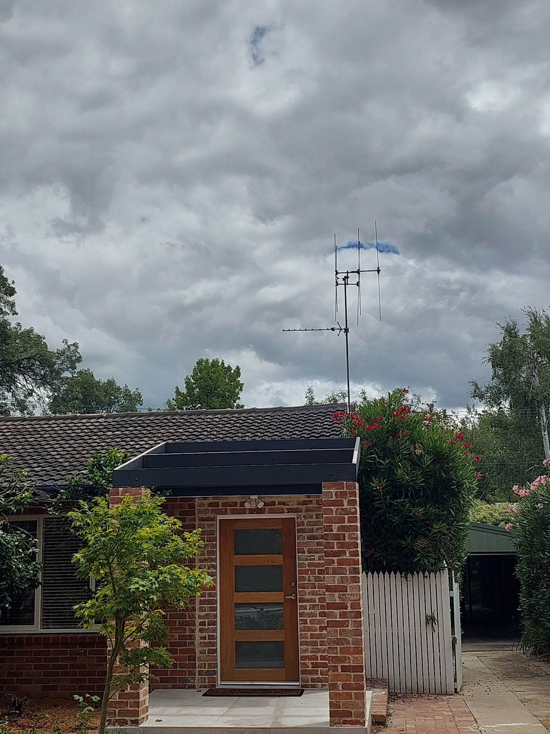 Brick Building With Wooden Door, Topped With an Antenna, Under a Cloudy Sky — Elimar Construction in Goulburn, NSW