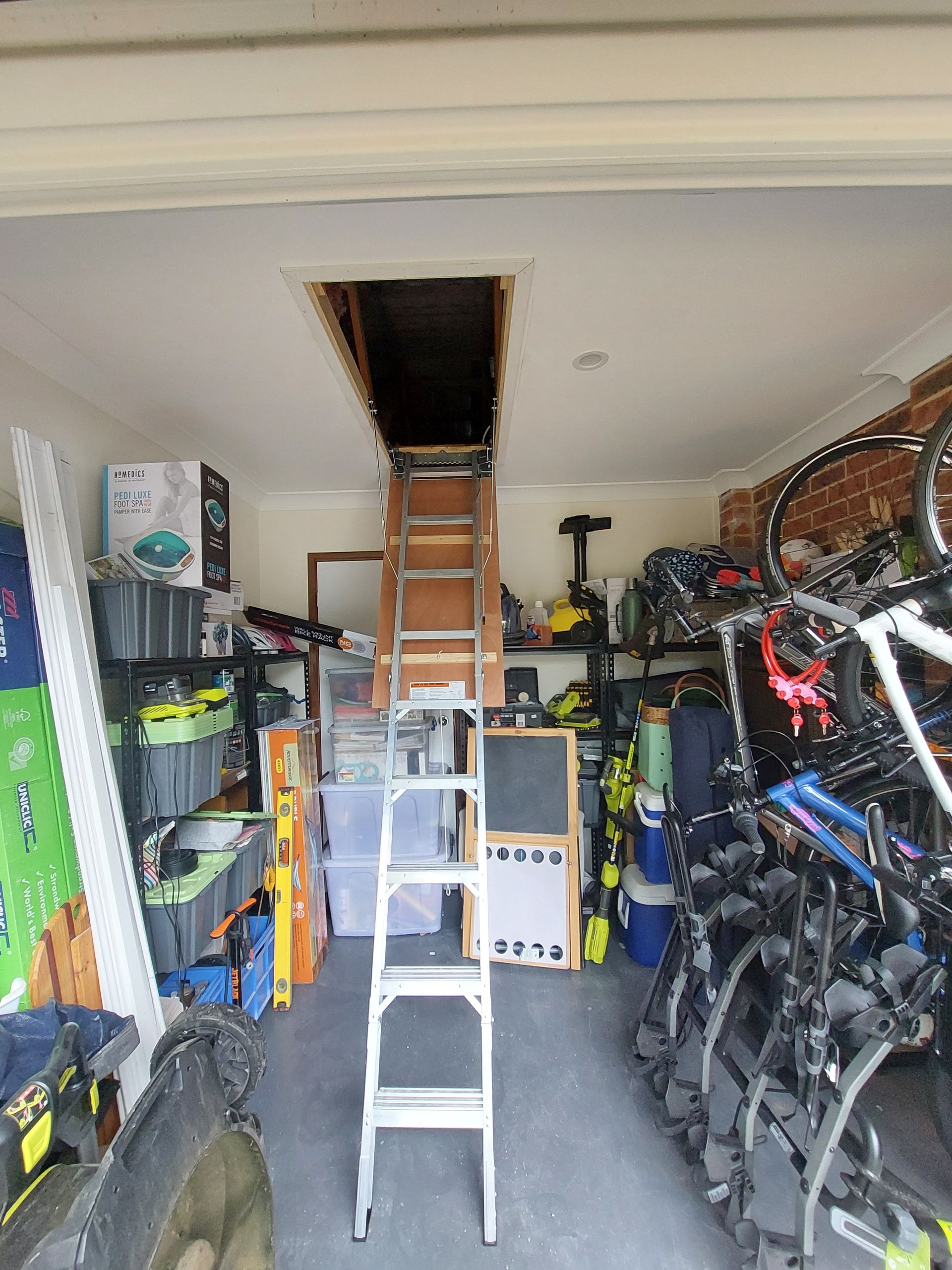 Garage Interior With a Pull-down Ladder Leading to an Attic Access. the Space is Filled With Stored Items — Elimar Construction in Goulburn, NSW