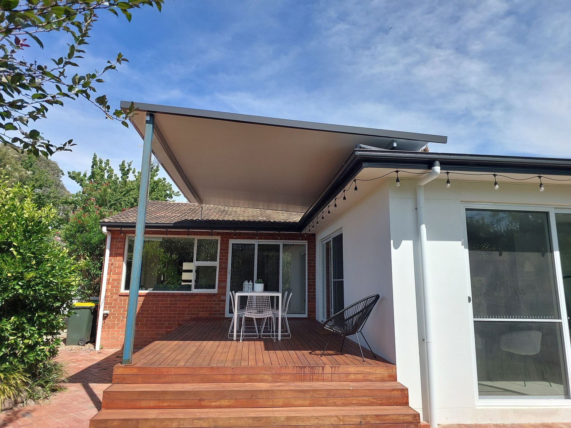 Backyard Deck With a Patio Cover. Table and Chairs Under the Cover. Wooden Deck and Red Brick Wall — Elimar Construction in Goulburn, NSW