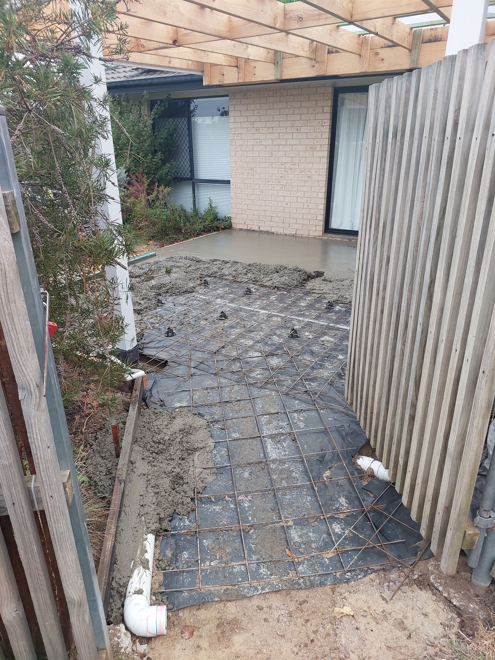 Muddy Walkway Leading to a House Entrance. Debris and a Corrugated Fence Are Visible — Elimar Construction in Goulburn, NSW