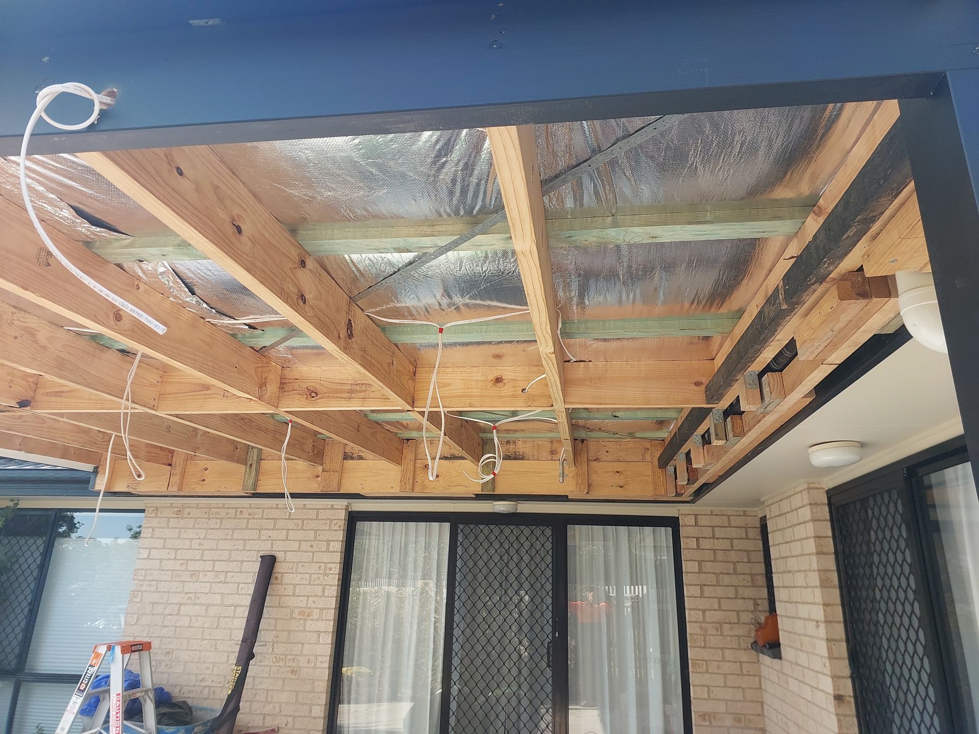 Wooden Patio Roof Under Construction With Insulation and Exposed Beams — Elimar Construction in Goulburn, NSW